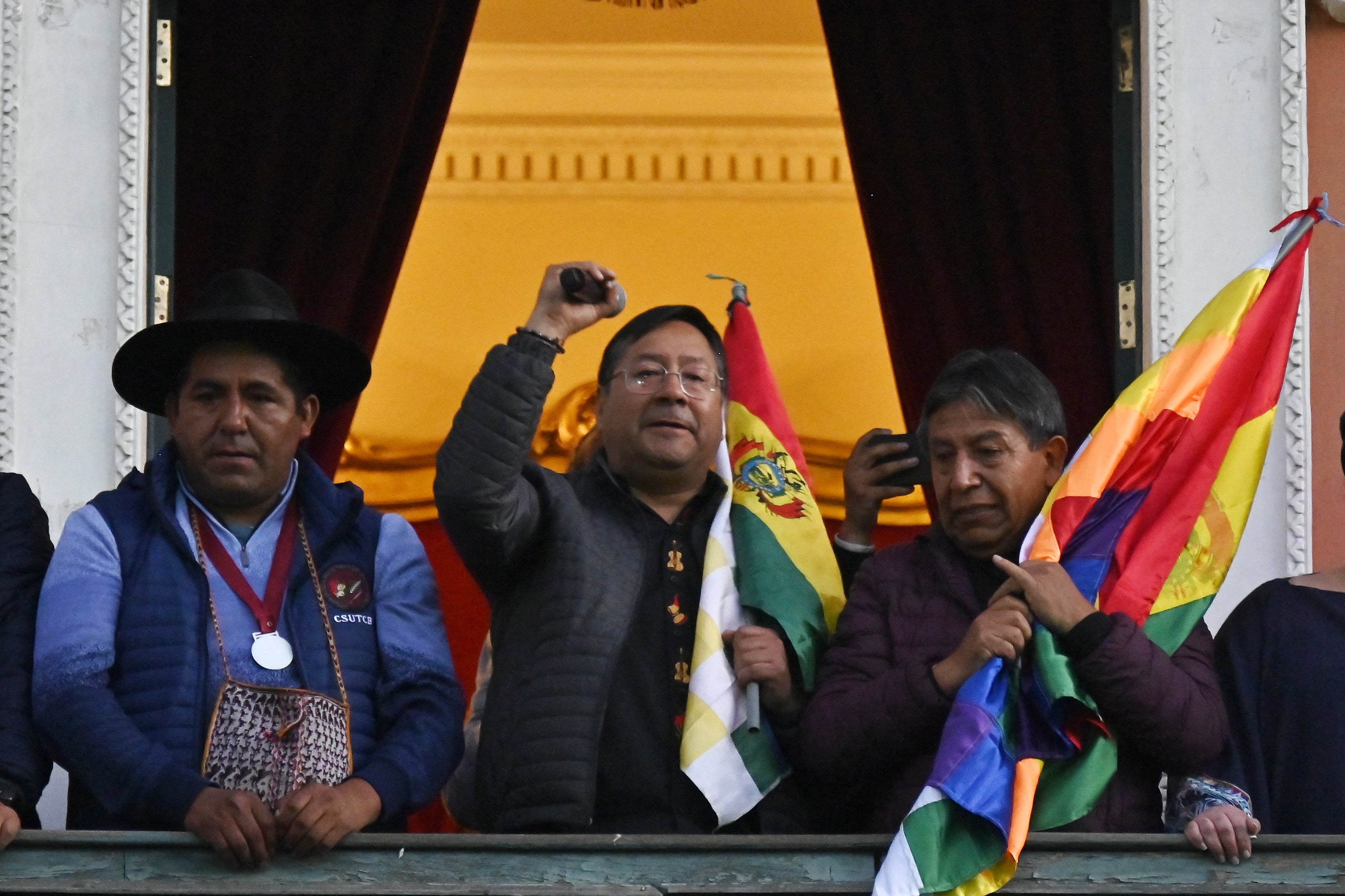 Bolivian President Luis Arce (C) talks from the balcony of the Government Palace in La Paz
