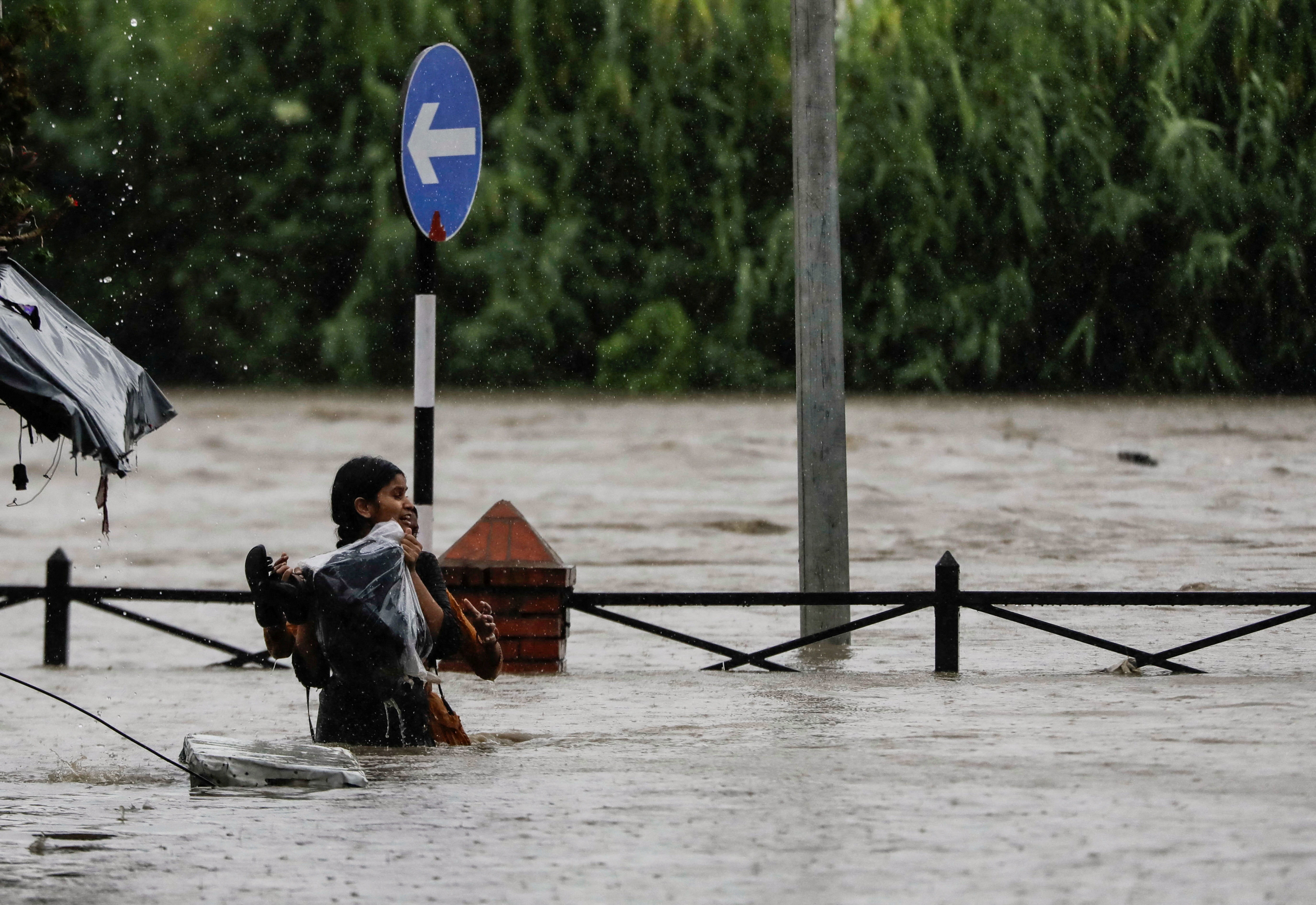 Una mujer carga con sus pertenencias al cruzar por una autopista inundada a lo largo de la orilla del desbordado río Bagmati tras las fuertes lluvias en Katmandú, Nepal