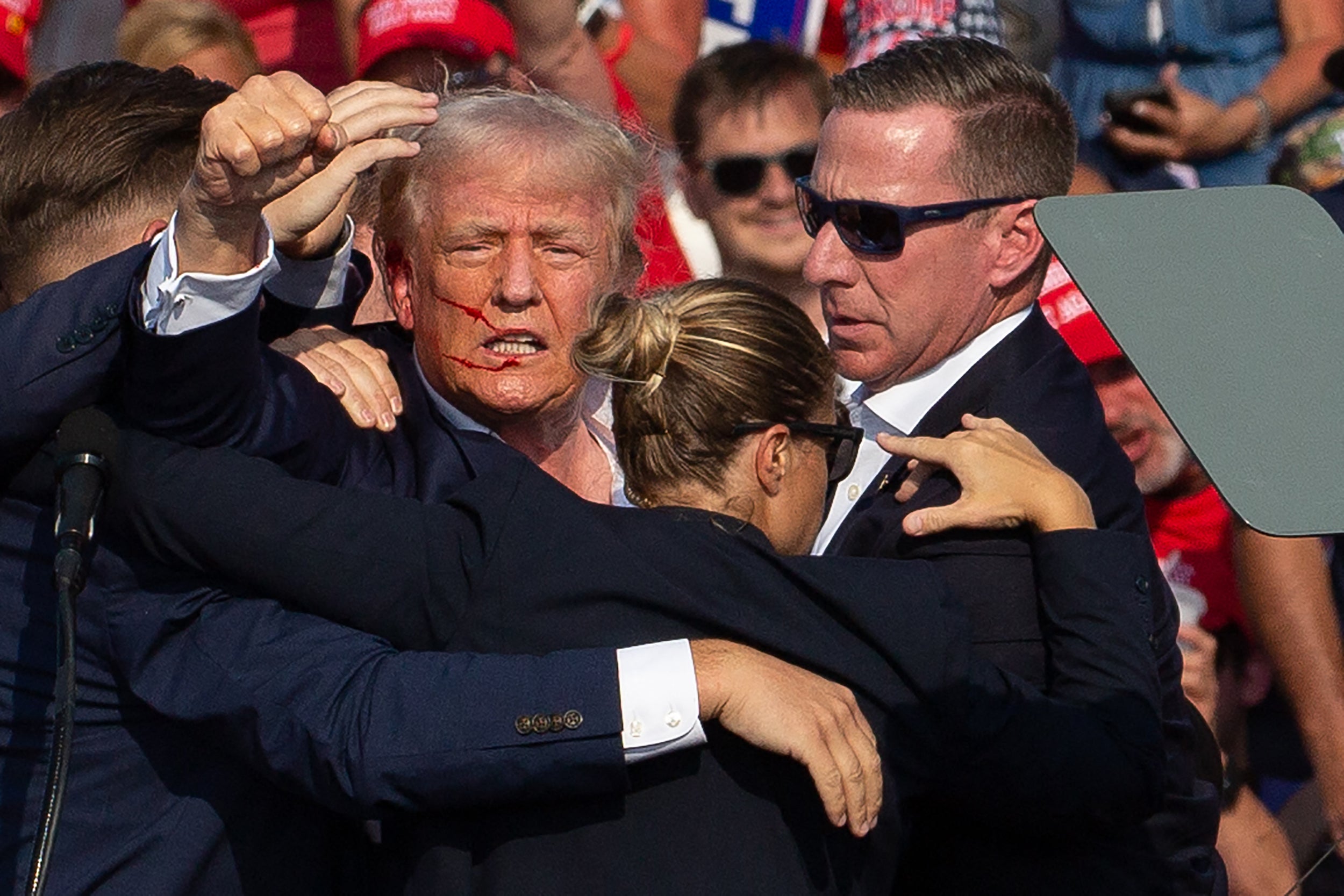 Donald Trump, con sangre en la cara rodeado de agentes del servicio secreto mientras lo sacan del escenario en un acto de campaña en Butler