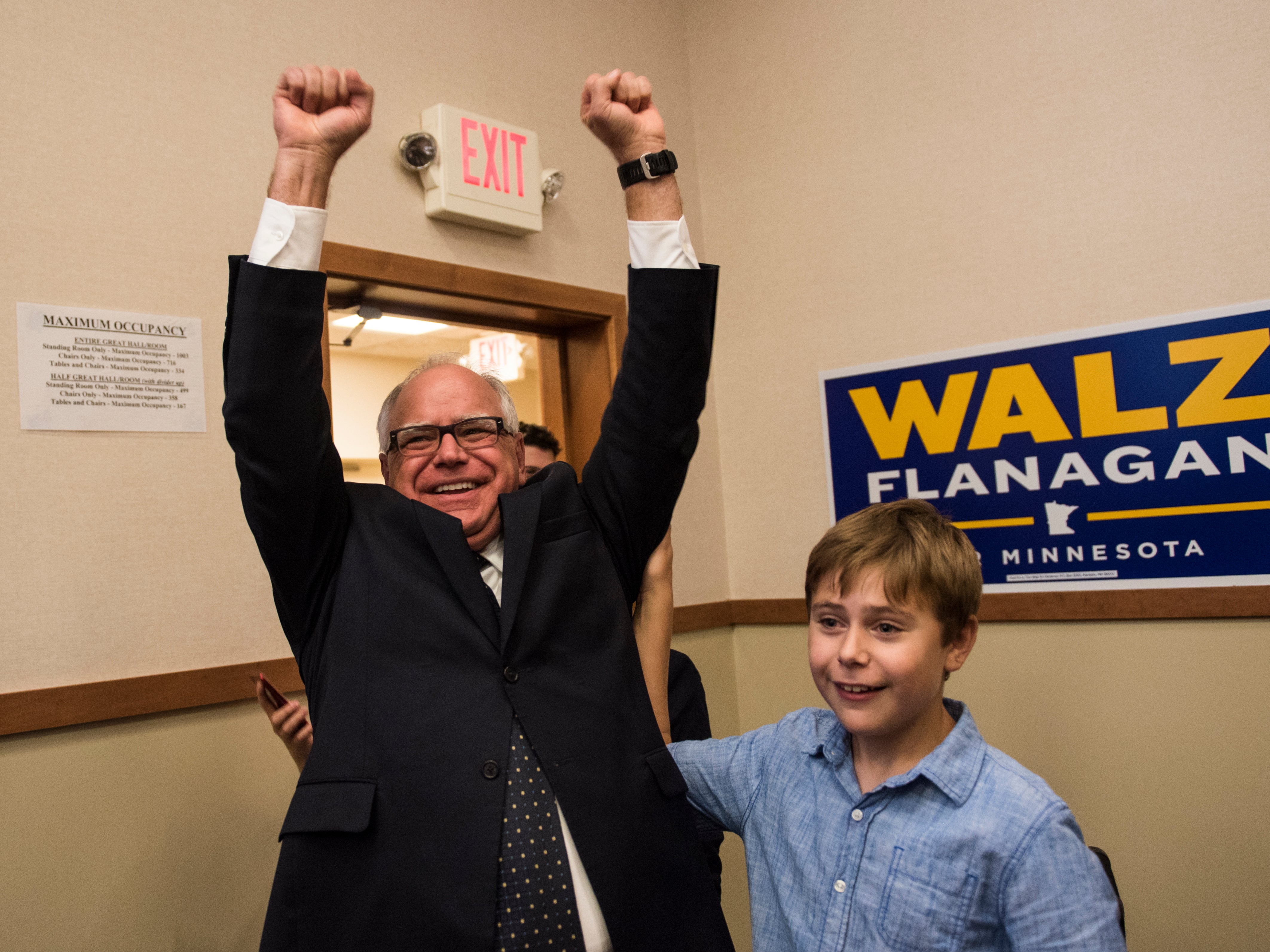 Tim Walz y su hijo Gus Walz celebran al ingresar a su fiesta de la noche electoral el 14 de agosto de 2018 en St. Paul, Minnesota. Fue reelegido gobernador en 2022