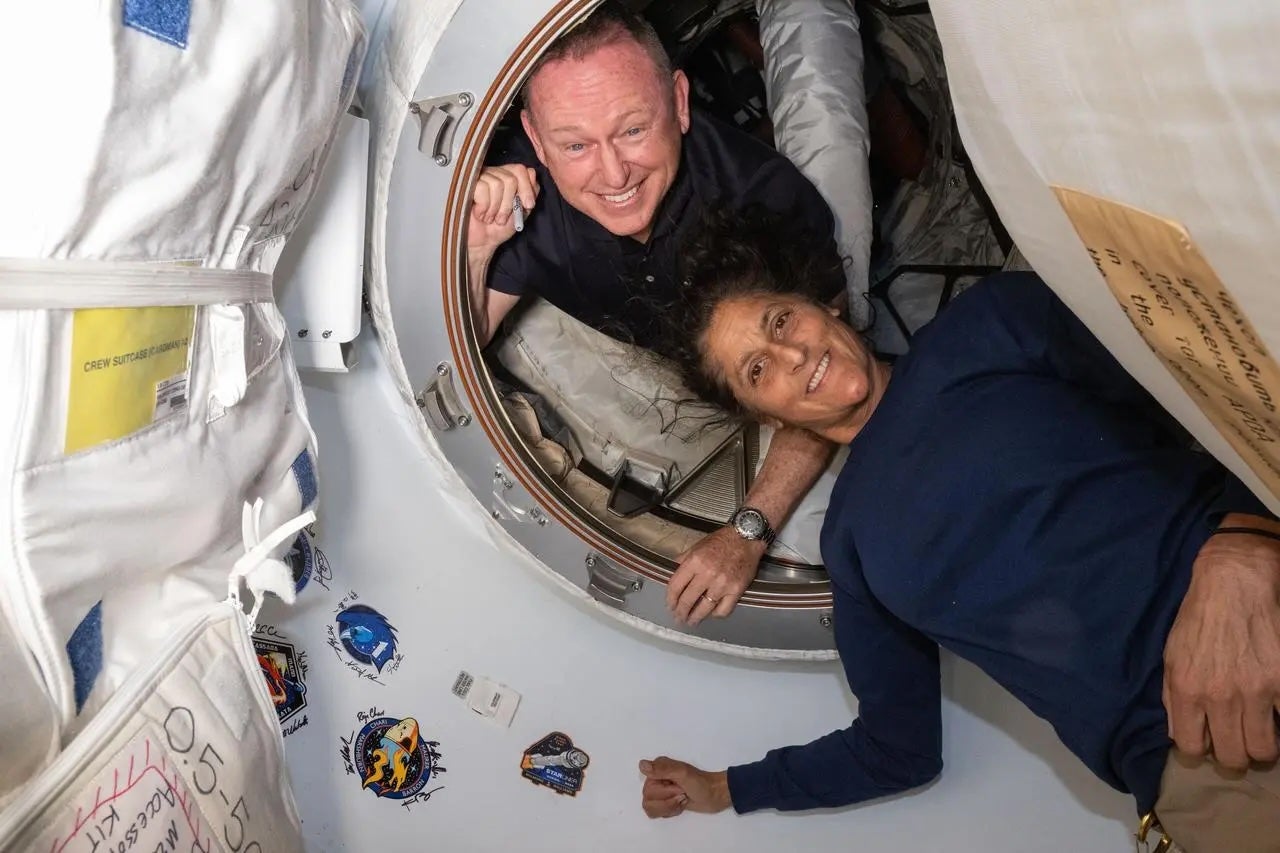 Los astronautas de la NASA Butch Wilmore y Suni Williams posan el 13 de junio de 2024 en el vestíbulo entre las naves espaciales Starliner de Boeing