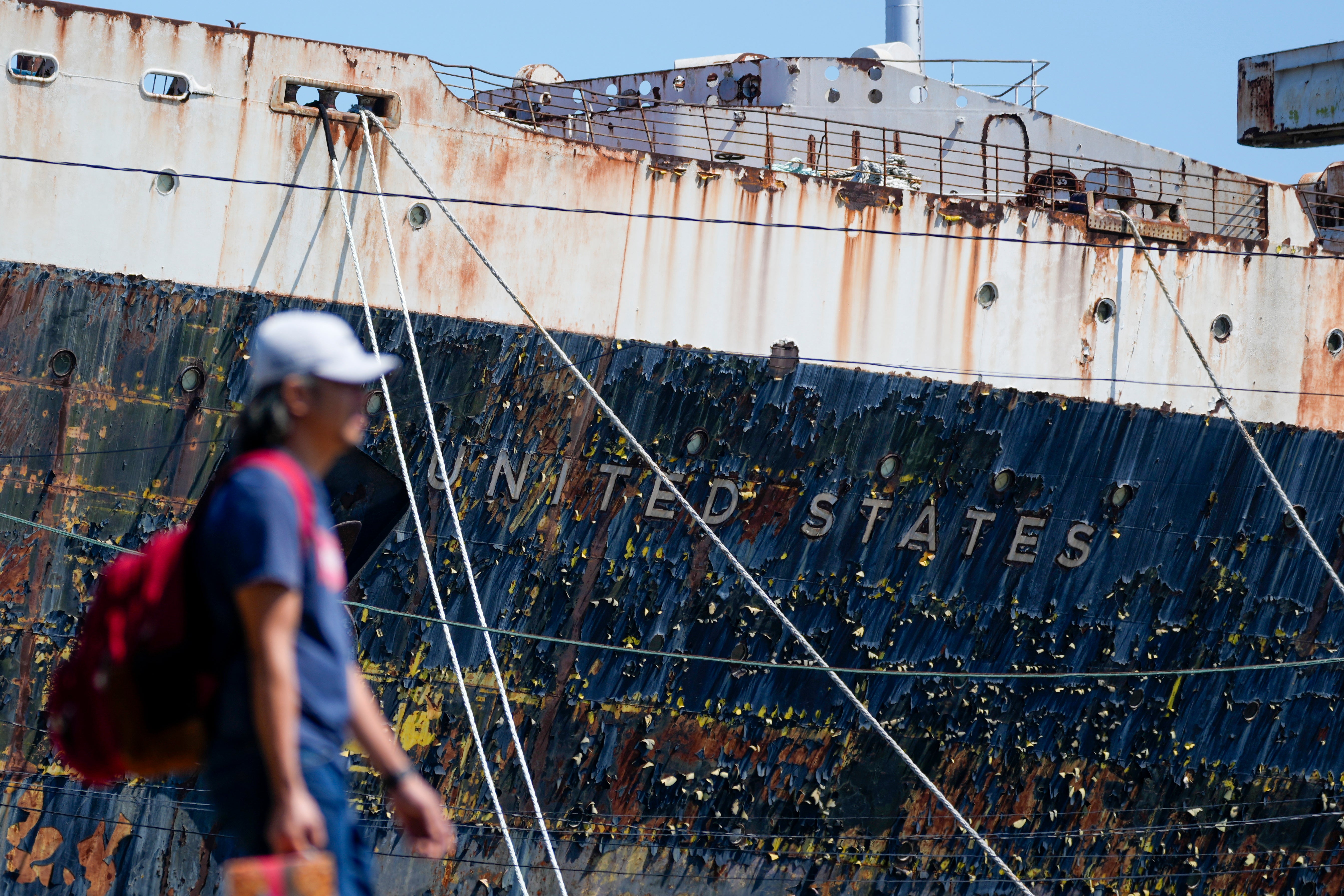 Una persona camina junto al SS United States amarrado en el río Delaware en Filadelfia