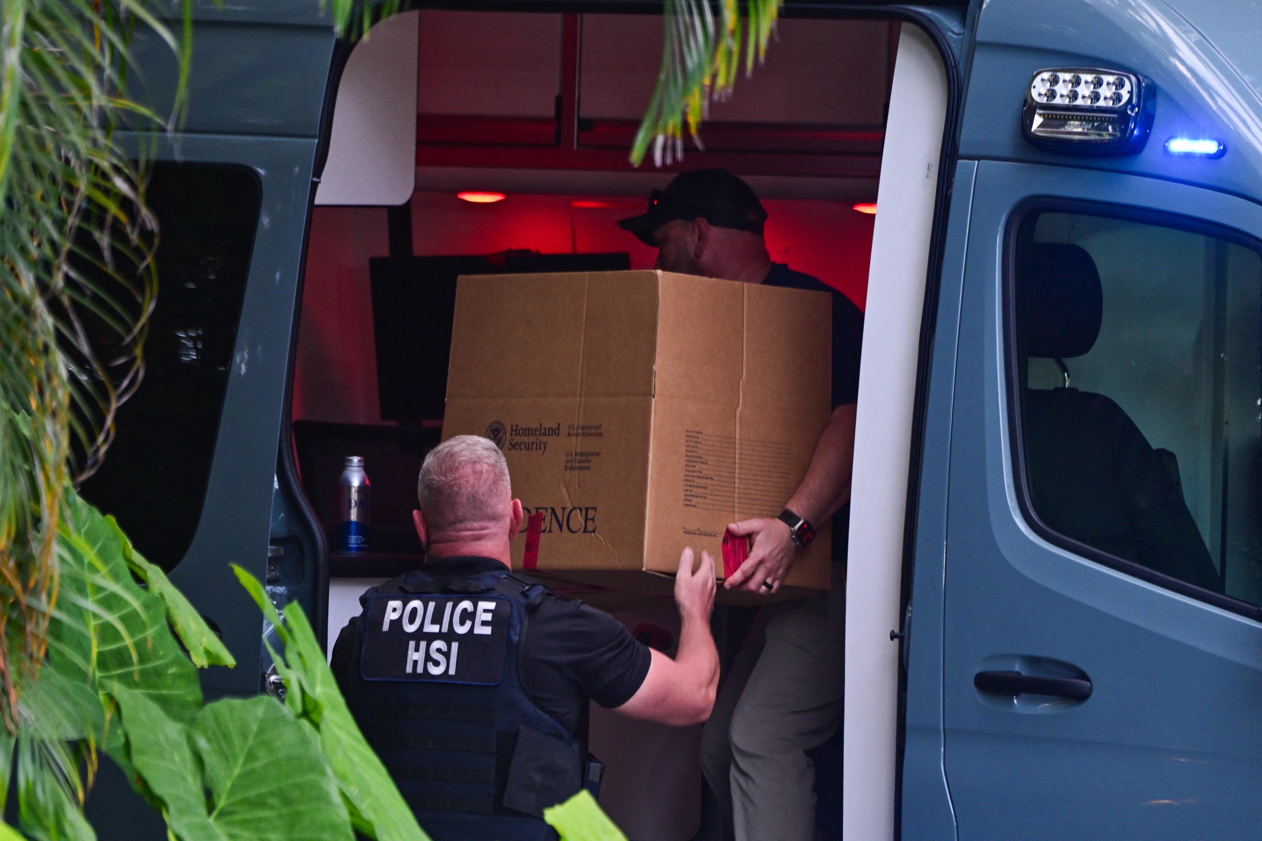 Agentes de Homeland Security Investigations cargan una caja en un automóvil frente a la entrada de la casa de Diddy en Miami, en marzo