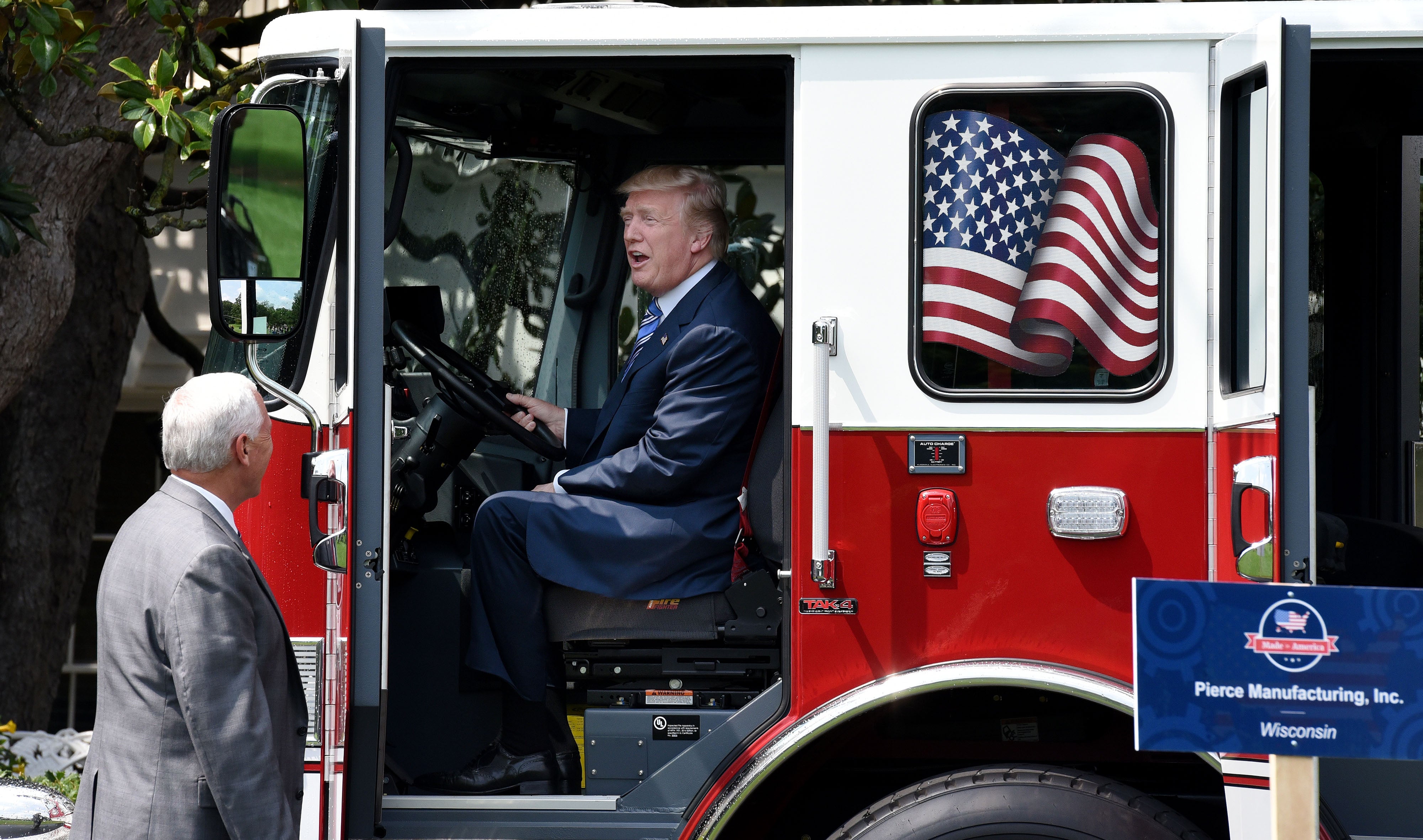 Trump sonríe sentado en un camión de bomberos mientras el entonces vicepresidente Mike Pence observa durante un evento de exhibición de productos Made in America en el Jardín Sur de la Casa Blanca, el 17 de julio de 2017