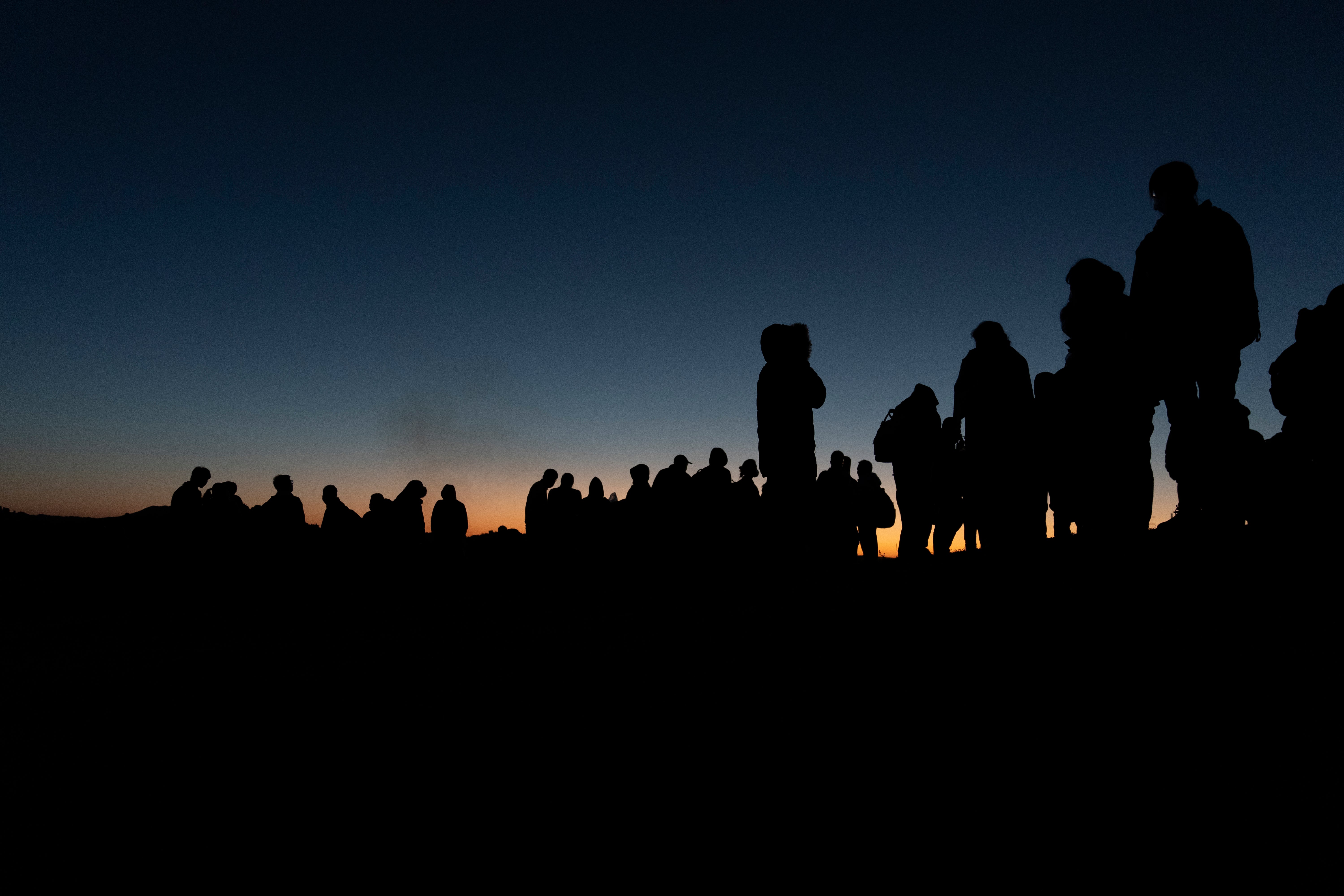 Migrantes chinos esperan a ser procesados tras cruzar la frontera con México en mayo de 2024 cerca de Jacumba Hot Springs, California