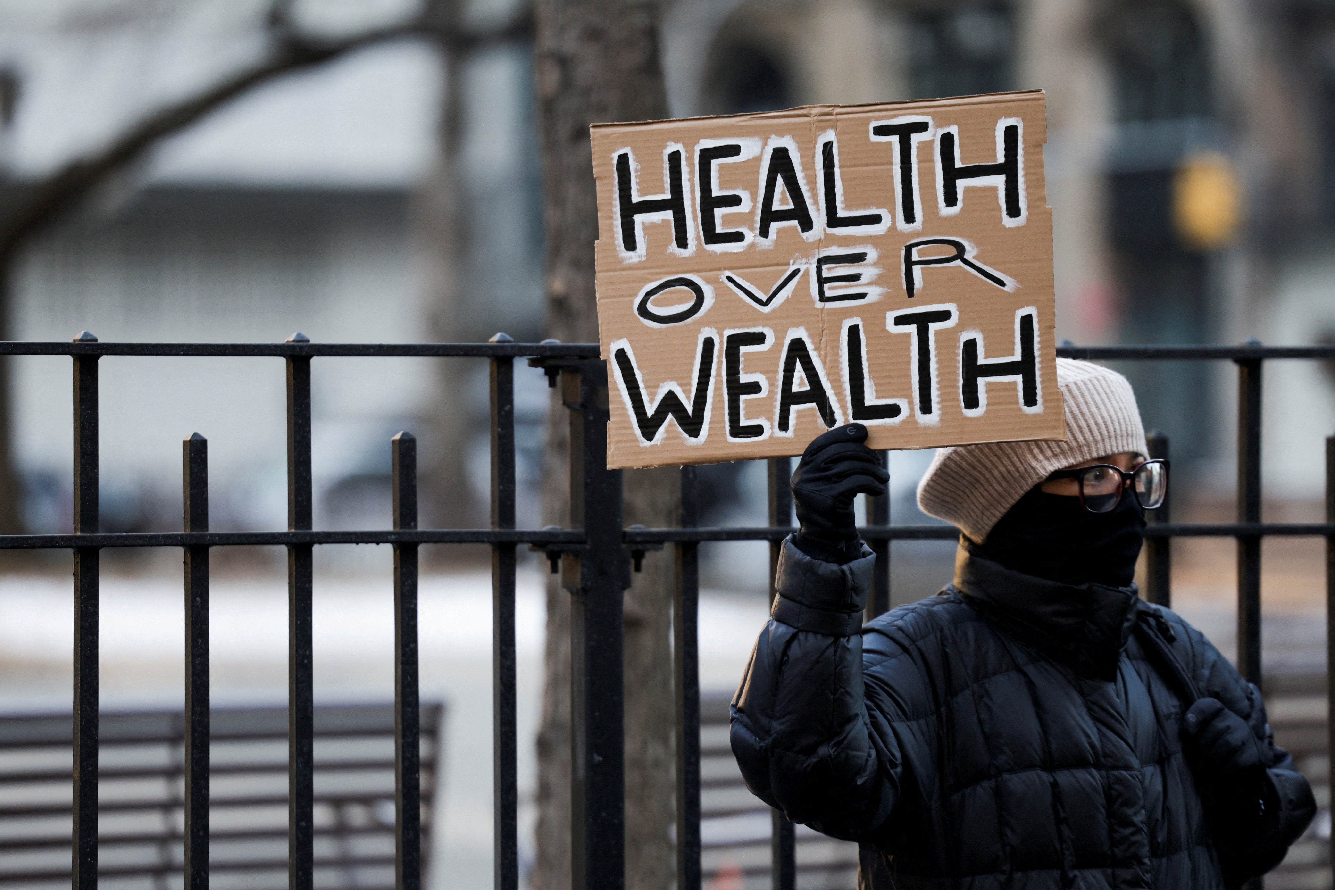 En las afueras del juzgado de Manhattan, el lunes por la mañana, un manifestante sostiene un cartel en el que se lee: “Salud antes que riqueza”