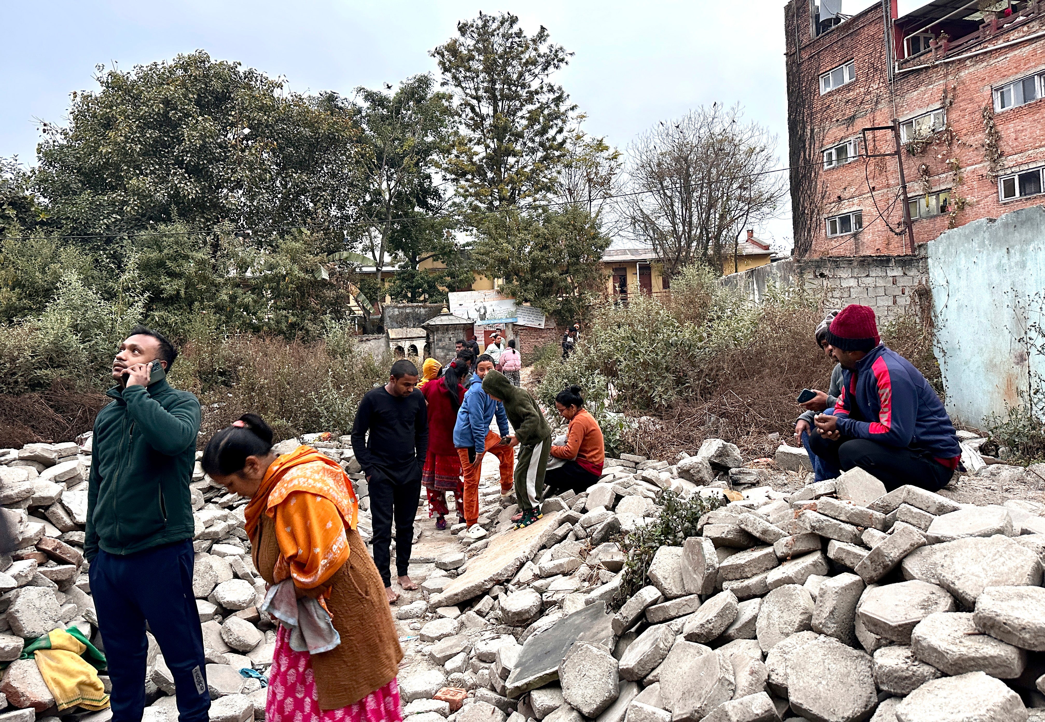 Nepalíes miran tras salir corriendo de sus casas después de sufrir un terremoto en Katmandú