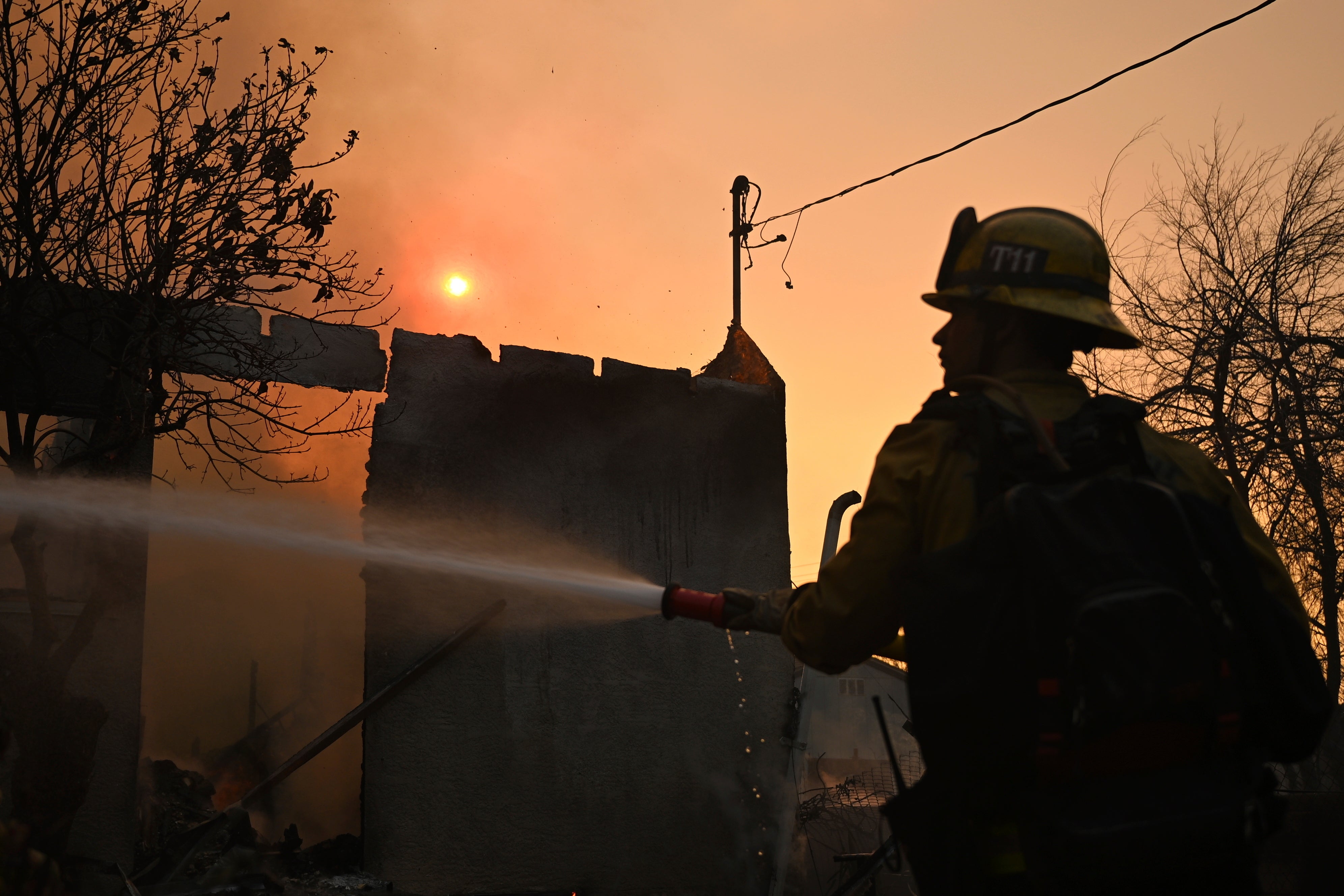 Un bombero riega una casa tras el incendio Eaton en Altadena, California. Algunos se preguntan si el agua de mar puede utilizarse para combatir las llamas