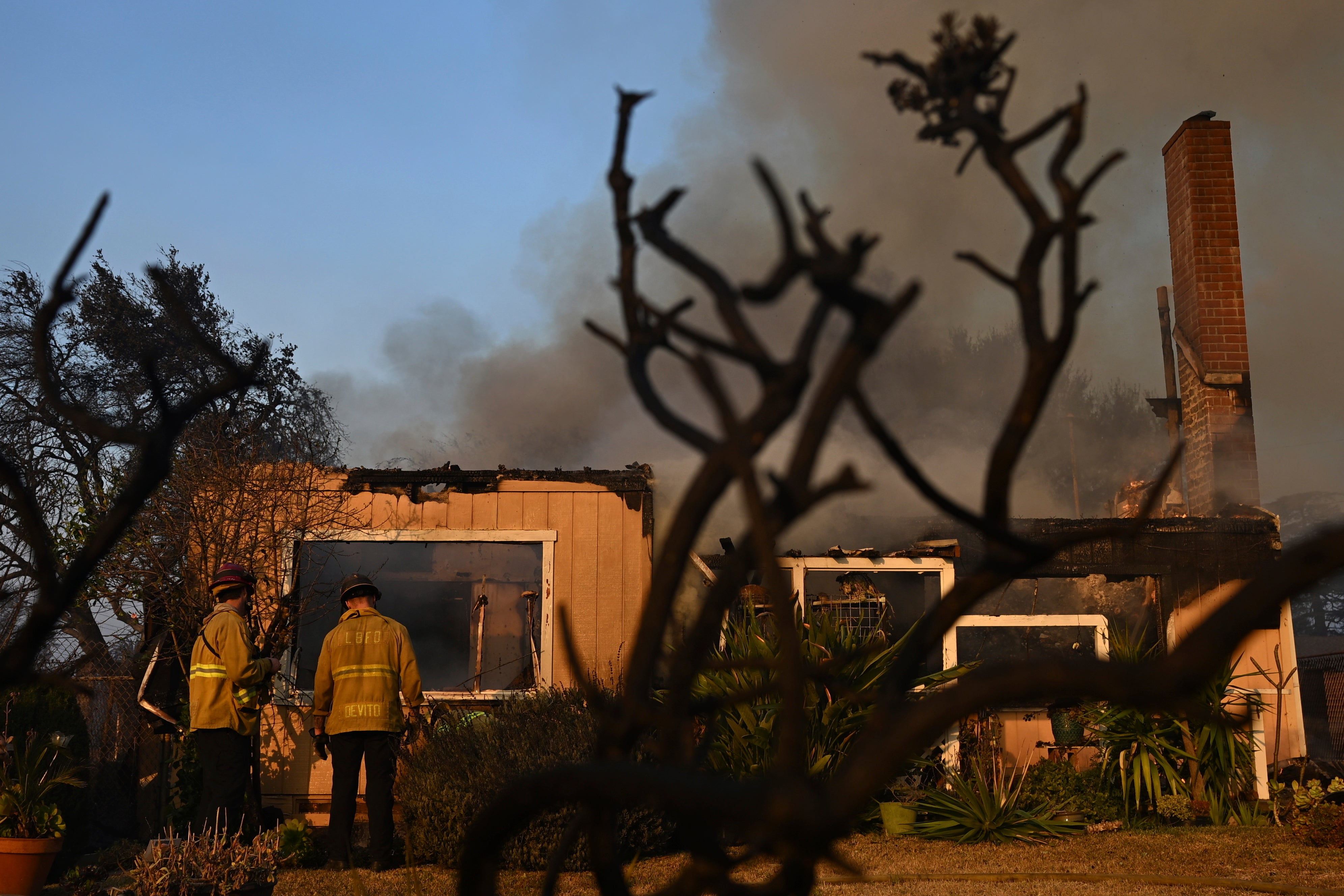 Los bomberos miran por encima de una casa después de que el incendio Eaton quema en Altadena, California, jueves, enero. 9, 2025