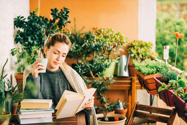 <p>Una mujer leyendo en el balcón (Alamy/PA)</p>