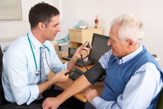 <p>Médico británico tomando la presión a un hombre mayor en un consultorio durante un chequeo</p>