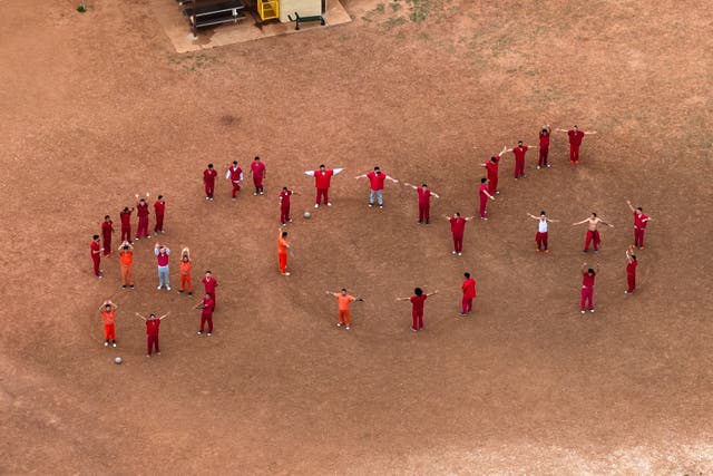<p>Reclusos venezolanos formando las letras “SOS” con sus cuerpos en el patio del centro de detención Bluebonnet en Anson, Texas, el lunes 28 de abril</p>