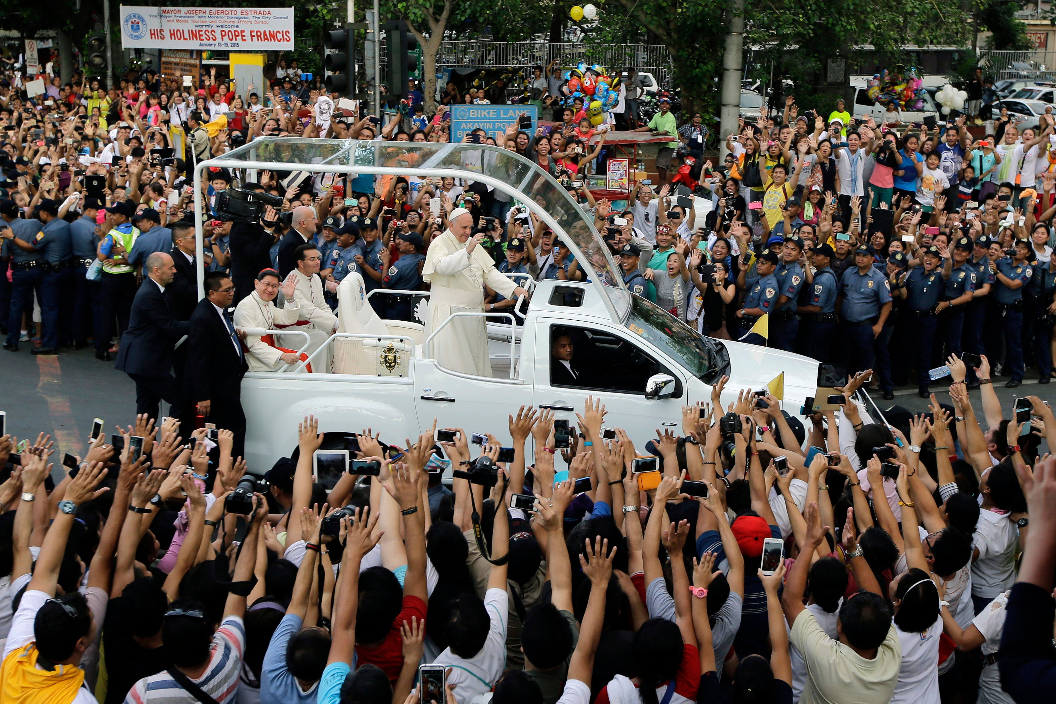 El papa Francisco saluda a los espectadores desde su papamóvil mientras su caravana pasa de camino a otro “Encuentro con las familias” en el Mall of Asia Arena en Manila, Filipinas