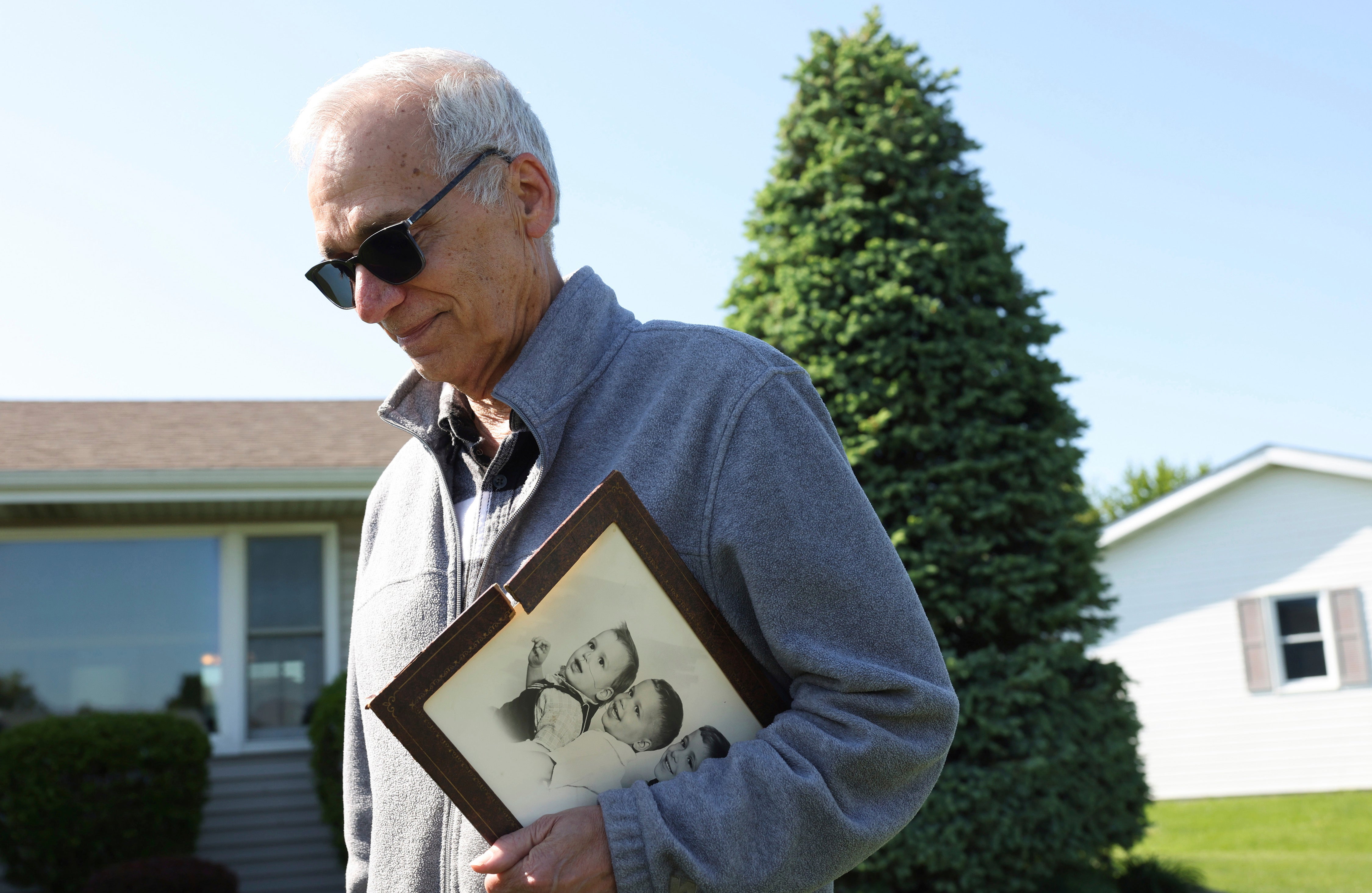 John Prevost, hermano del nuevo papa León XIV, sostiene un retrato de los tres hermanos Prevost de 1958