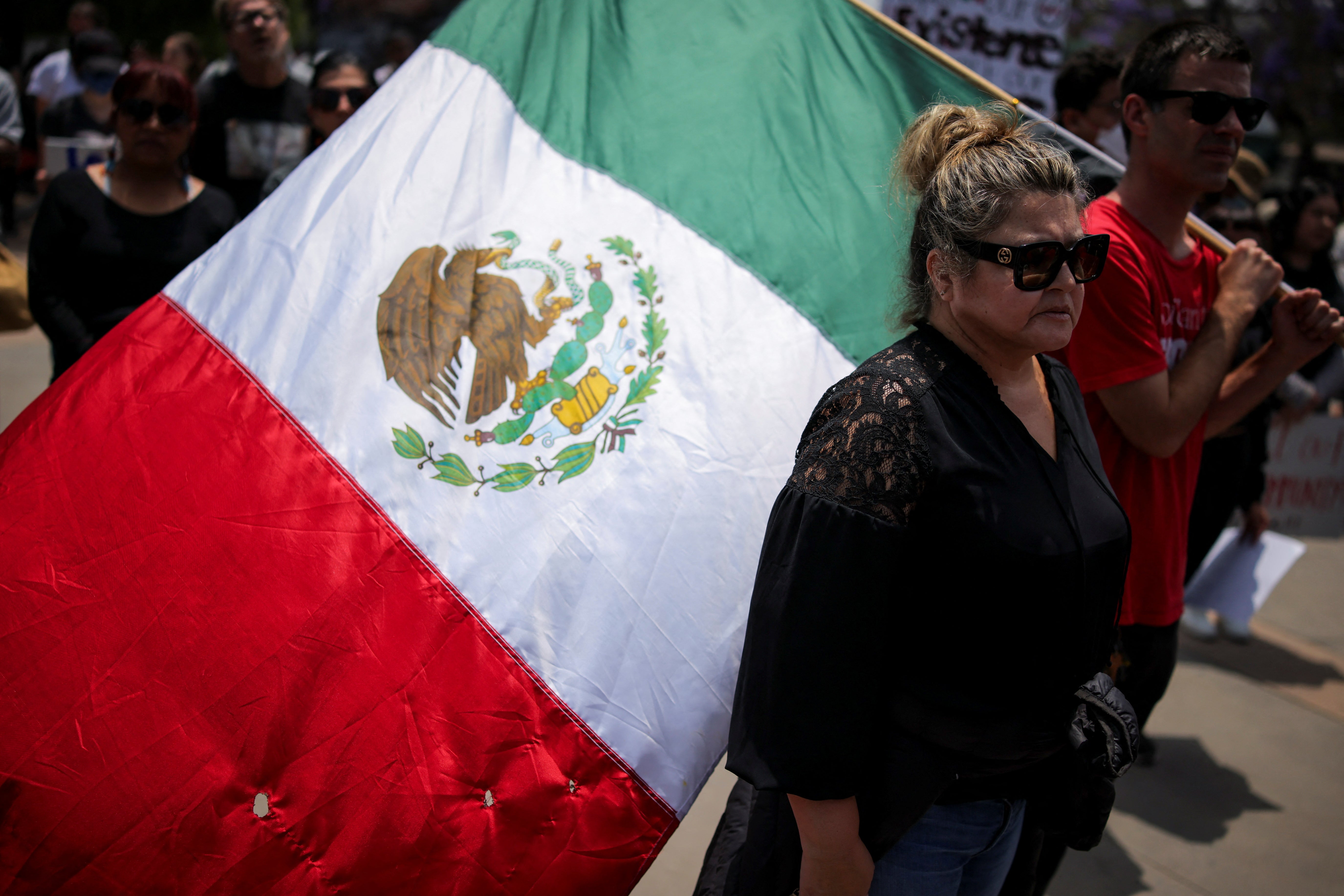 Una mujer junto a un hombre con una bandera mexicana, en una protesta contra las redadas federales de inmigración en el barrio de Boyle Heights de Los Ángeles, California, el 8 de junio