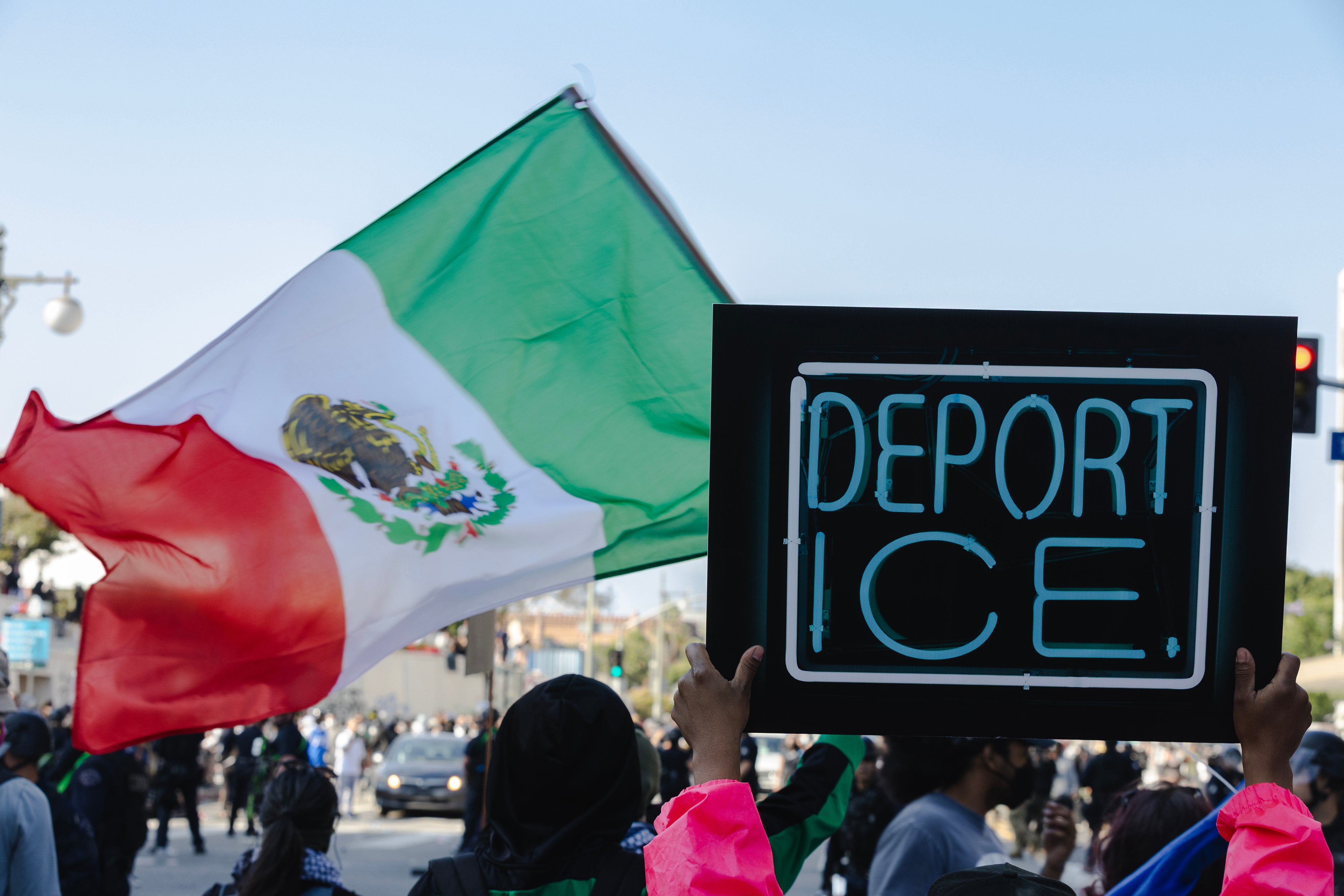 Manifestantes sostienen pancartas contra el ICE y una bandera mexicana durante los enfrentamientos con la policía en Los Ángeles