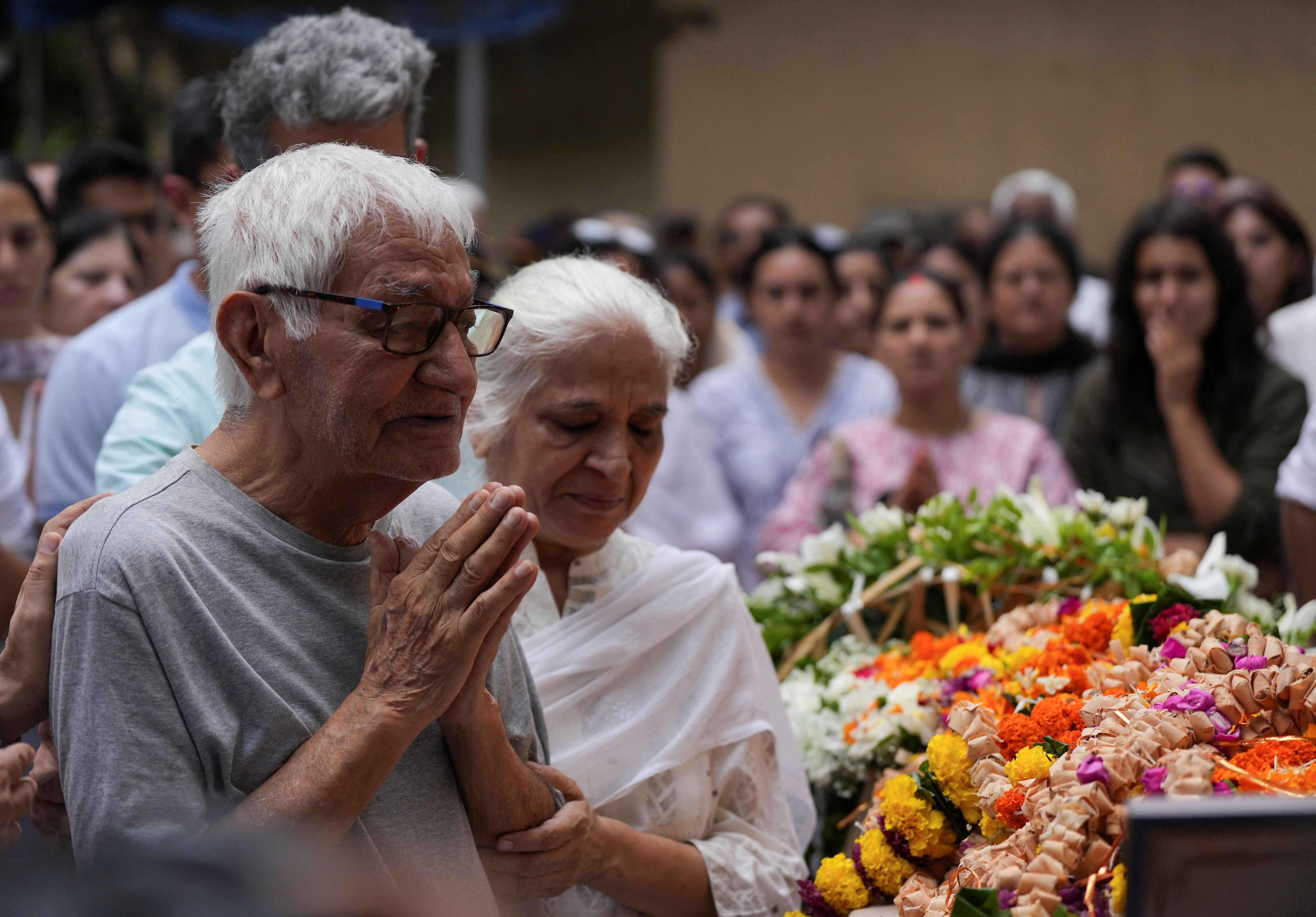 El padre y la madre del piloto Sumeet Sabharwal, fallecido al estrellarse un avión Boeing 787-8 Dreamliner de Air India durante el despegue de un aeropuerto, rezan junto al cuerpo de su hijo en Bombay, India, el 17 de junio de 2025