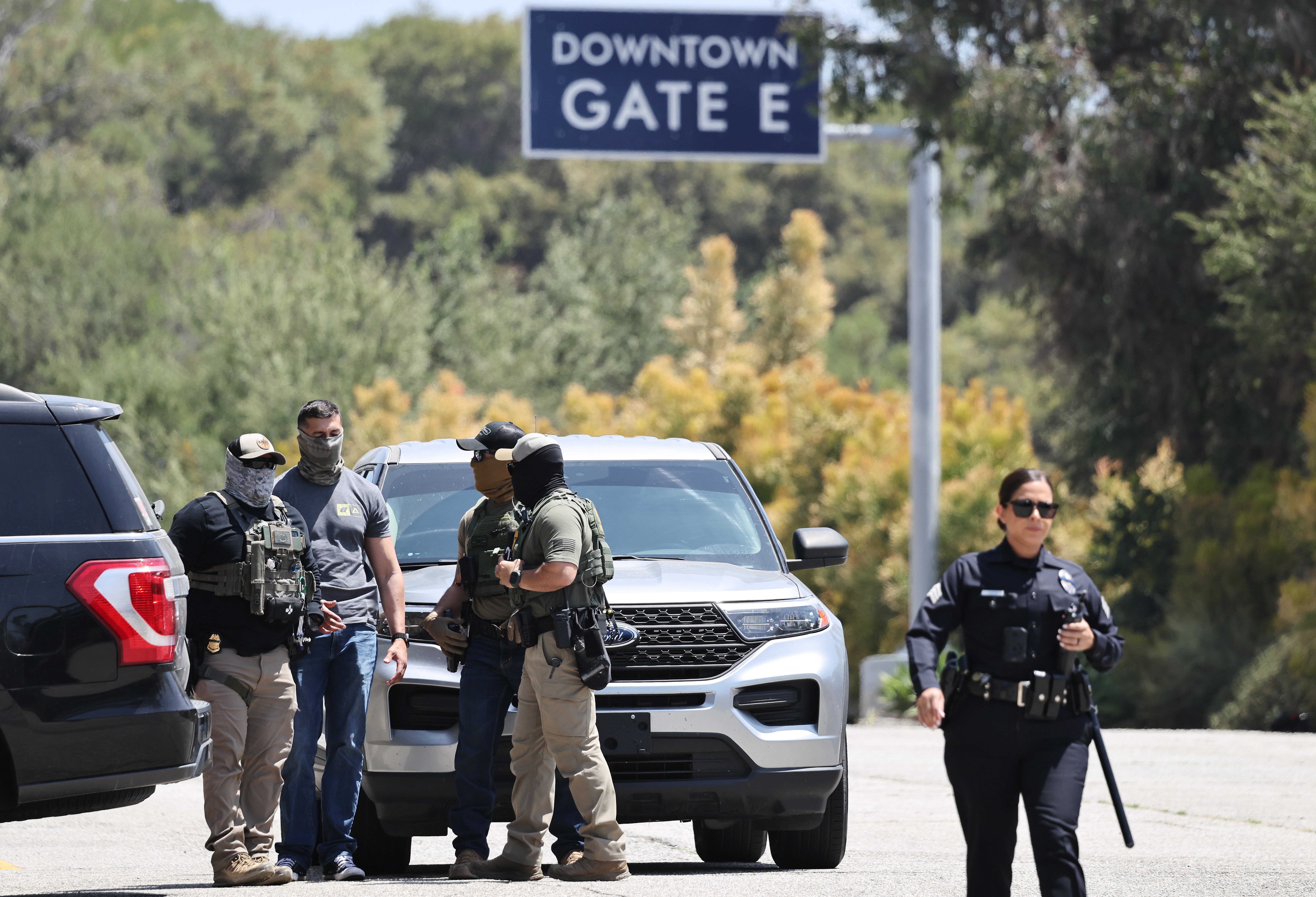 Oficial de policía de Los Ángeles pasa junto a agentes federales enmascarados en el Dodger Stadium