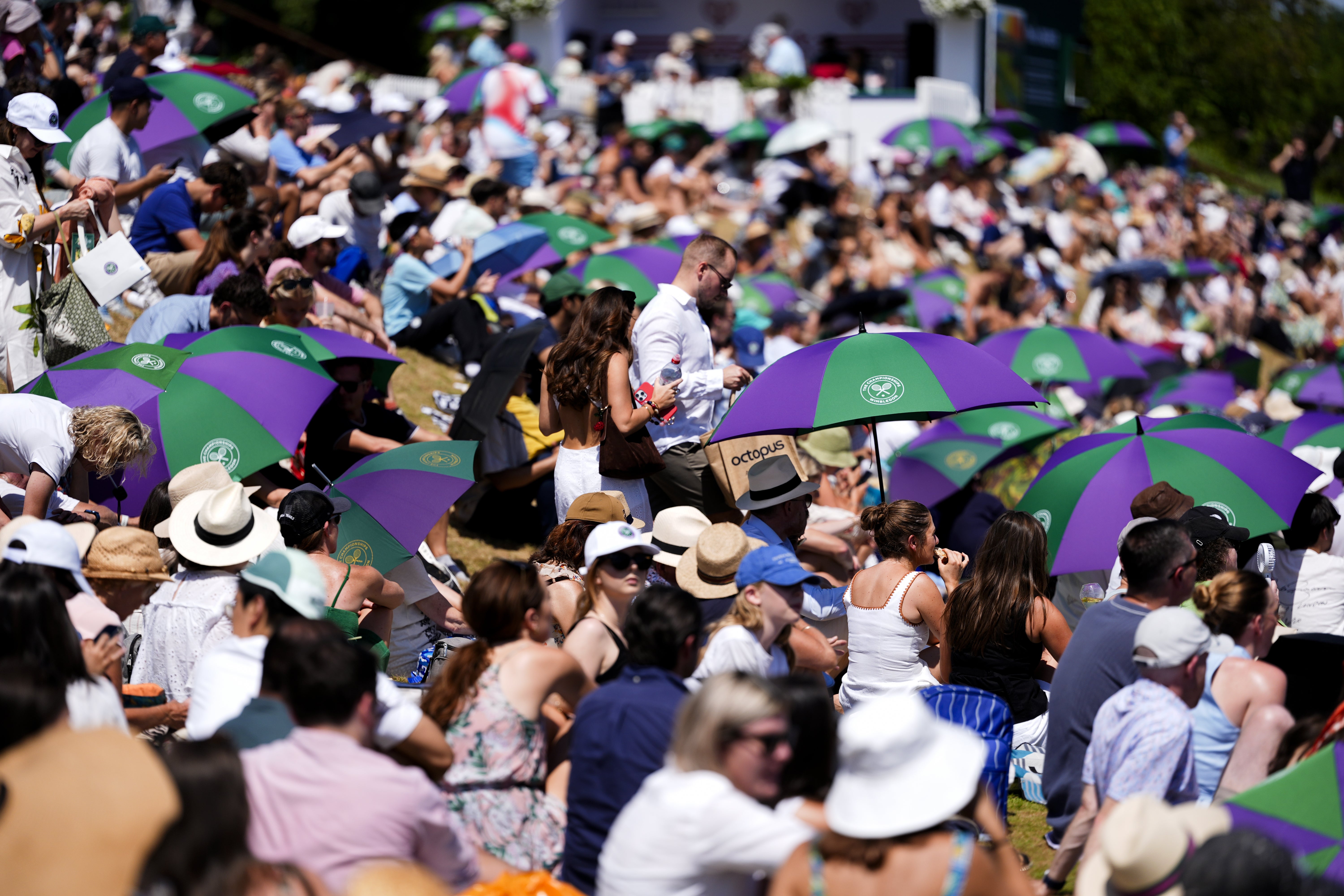 Spectators on Henman Hill shelter from the sun (Jordan Pettitt/PA)
