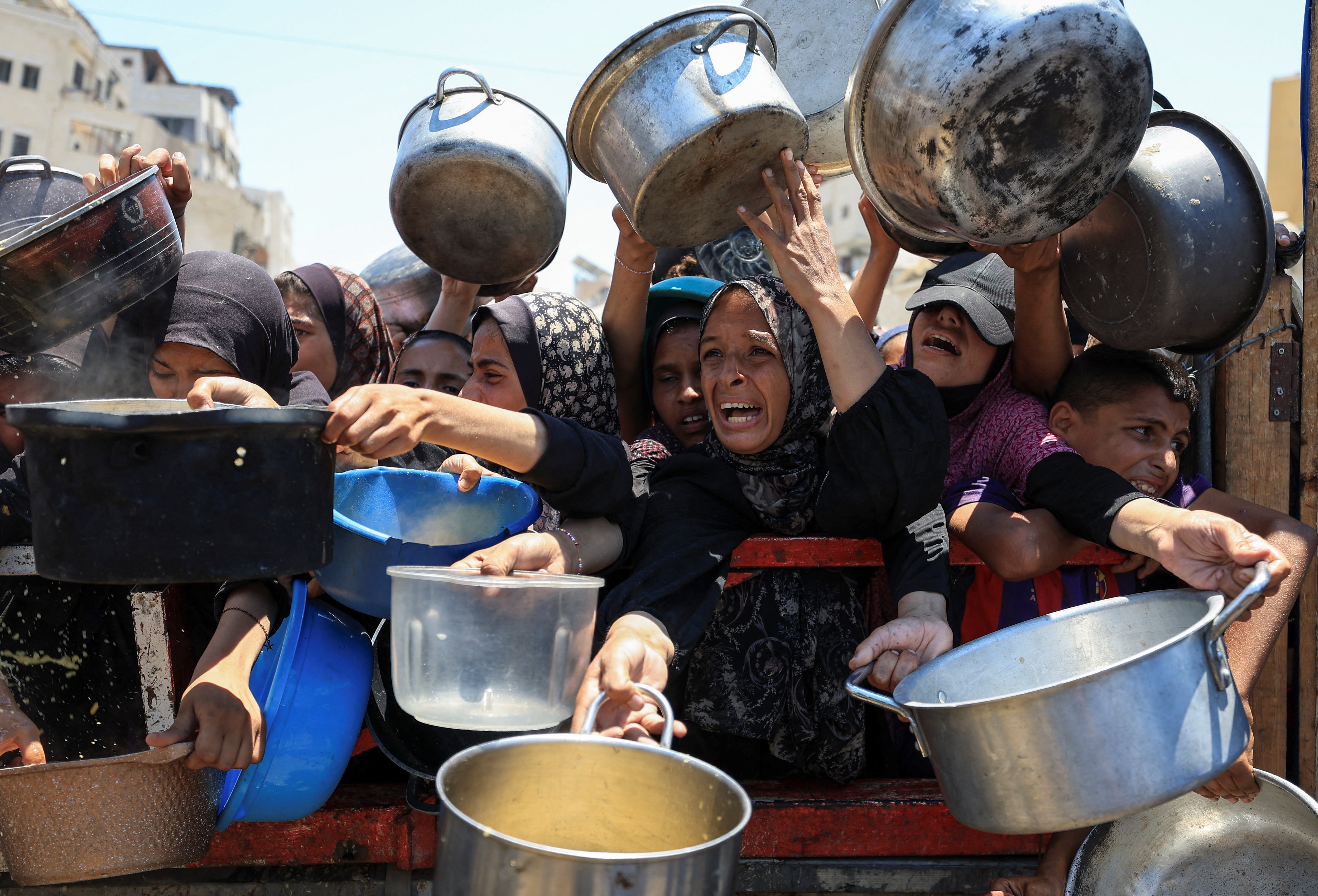 Palestinos se reúnen para recibir alimentos de una cocina benéfica en Gaza