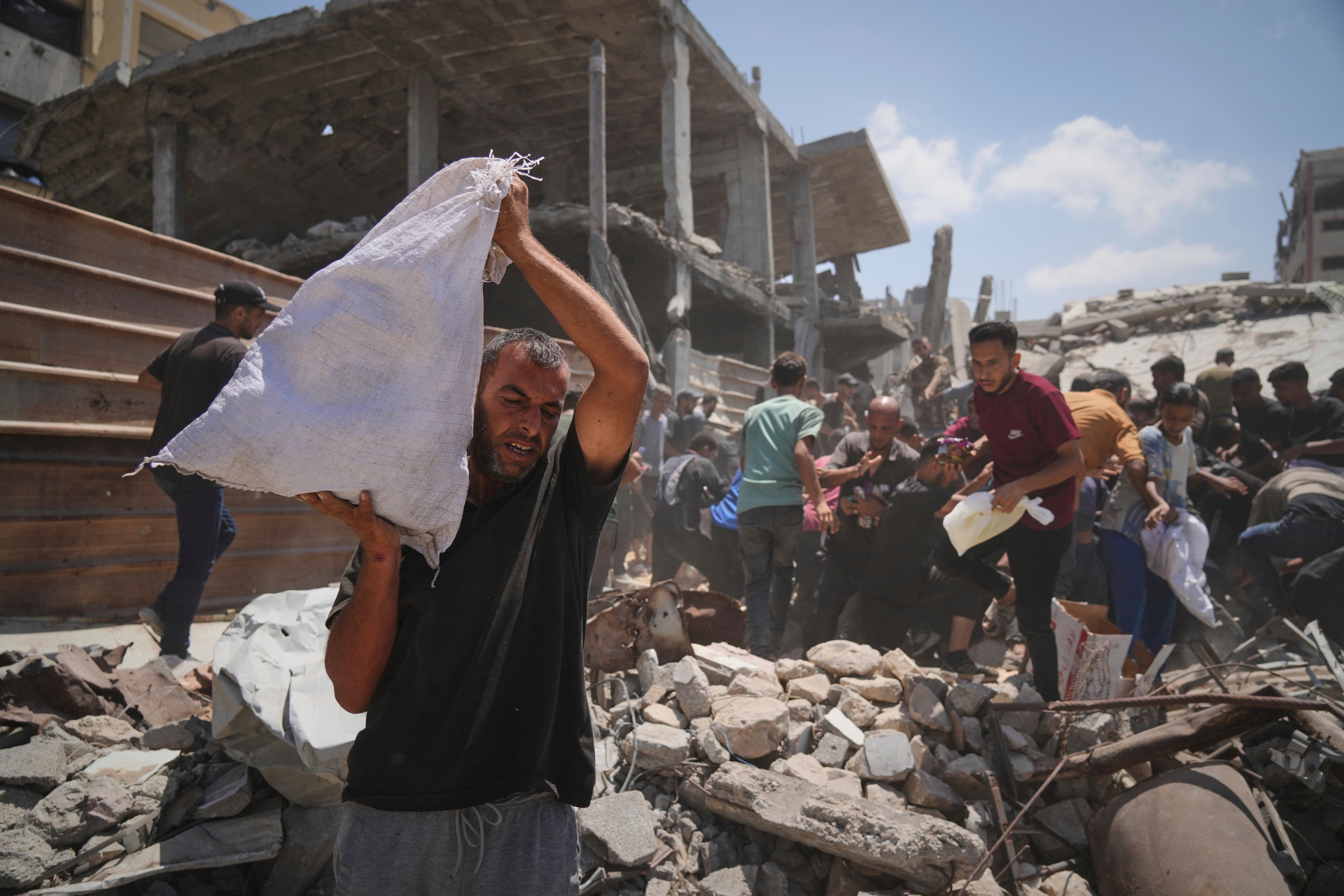 Palestinos luchan por recoger la ayuda humanitaria lanzada en paracaídas sobre la ciudad de Gaza, en el norte de la Franja de Gaza, el jueves 7 de agosto de 2025