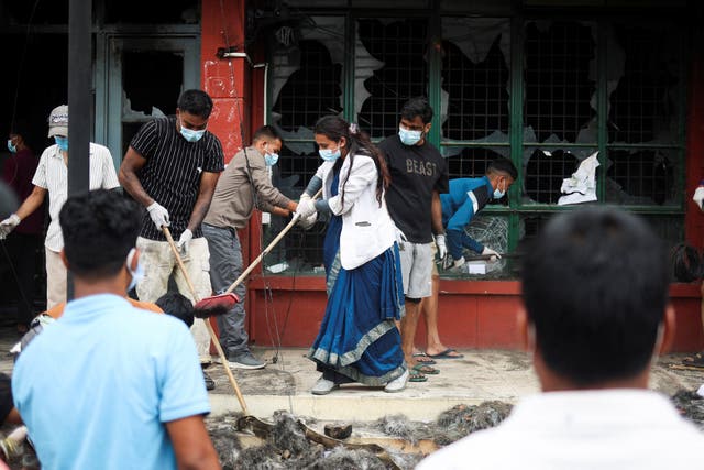 <p>Una mujer carga una escoba y una bolsa de basura mientras grupos de personas se dirigen a limpiar las calles de Katmandú, Nepal</p>