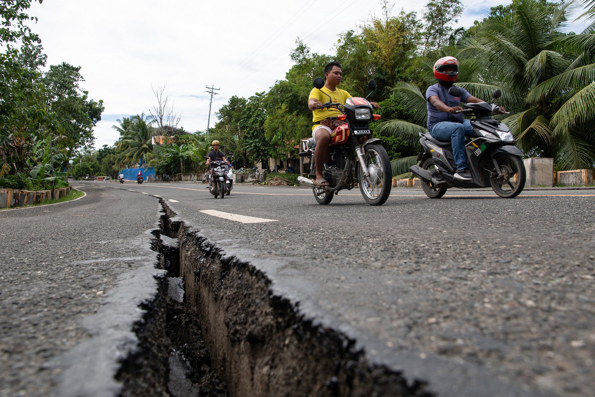 Varios automovilistas pasan junto a una grieta en la carretera en Tabogon, provincia de Cebú, en el centro de Filipinas