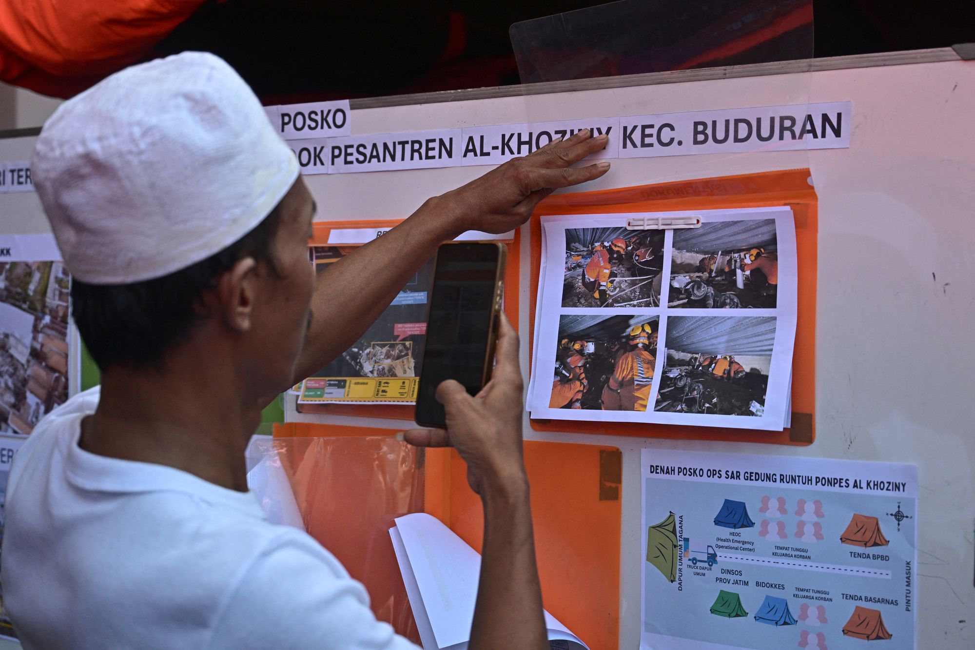 Un familiar mira las imágenes de un tablón de anuncios mientras continúan las labores de búsqueda y rescate en el internado islámico de Al Khoziny, en Sidoarjo