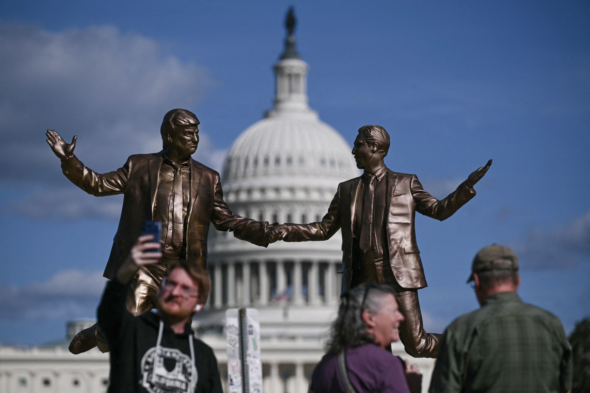 La gente posa para fotos cerca de la estatua de Epstein y Trump el jueves