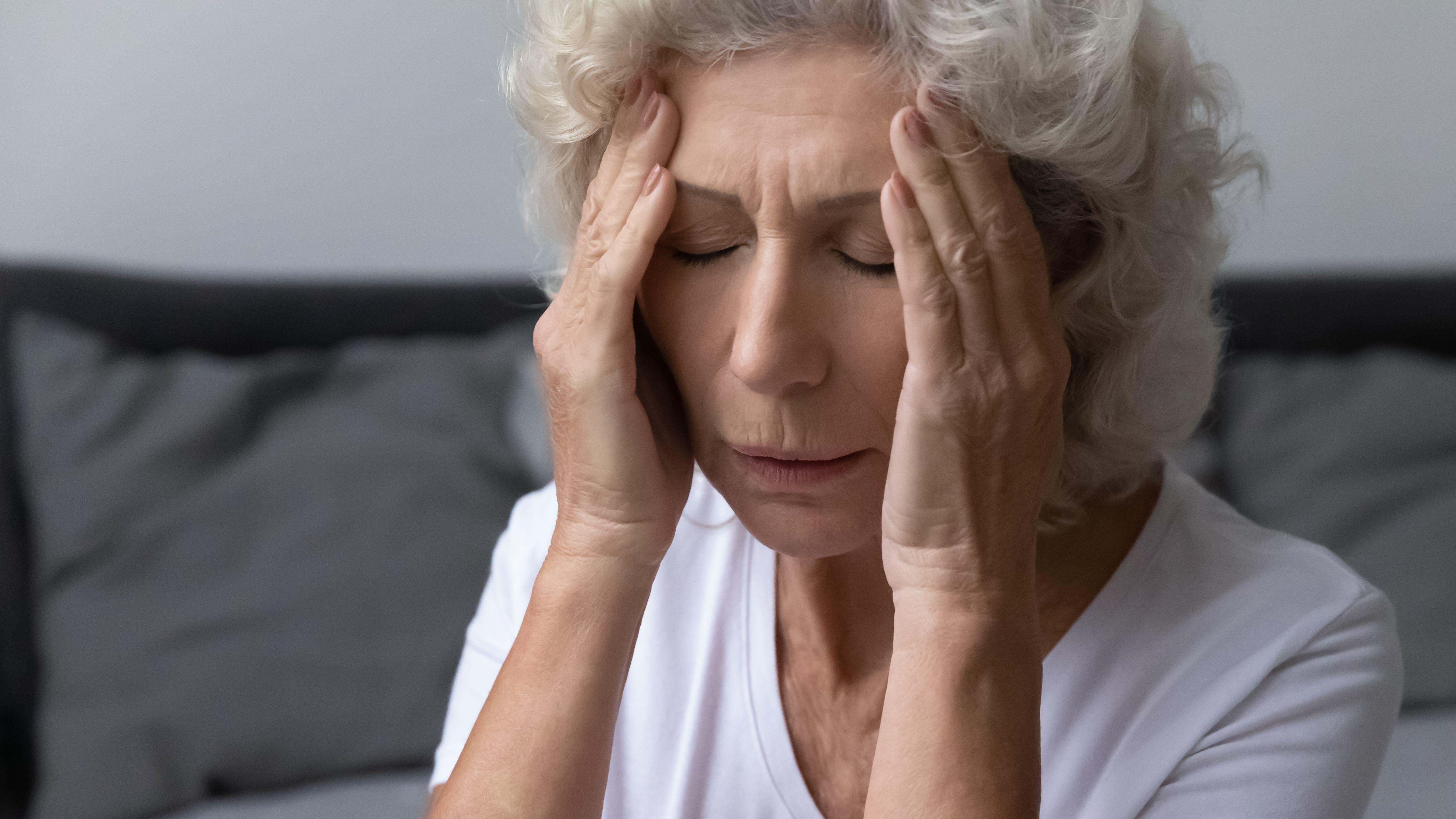 Mujer mayor estresada y frustrada que siente un fuerte dolor de cabeza