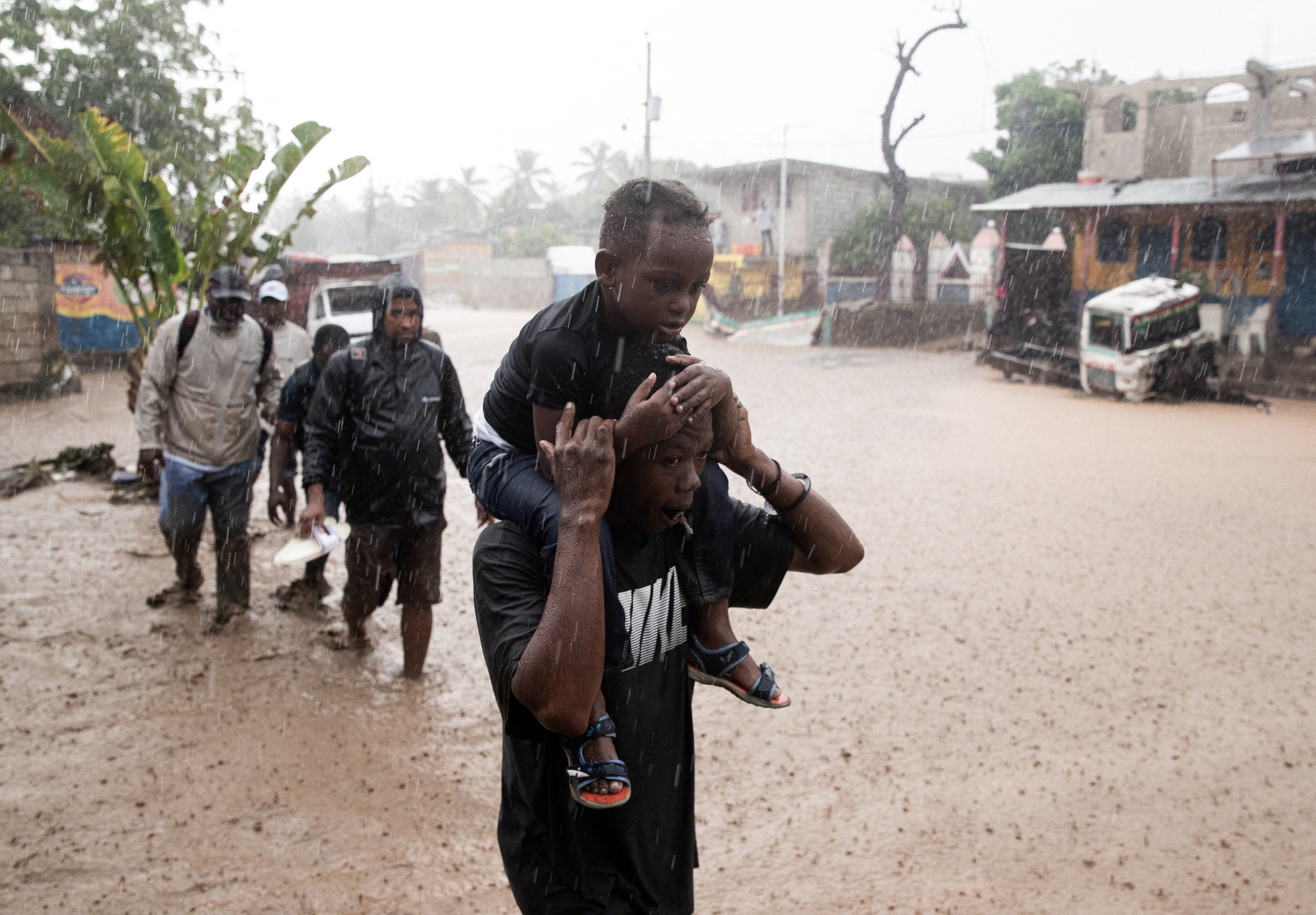 El jueves, tras el paso del huracán Melissa, varias personas caminaron por una calle inundada en Petit-Goâve, Haití. Gran parte de los daños provocados por los huracanes se debe a las intensas precipitaciones, ya que una atmósfera más cálida puede retener mayor cantidad de humedad