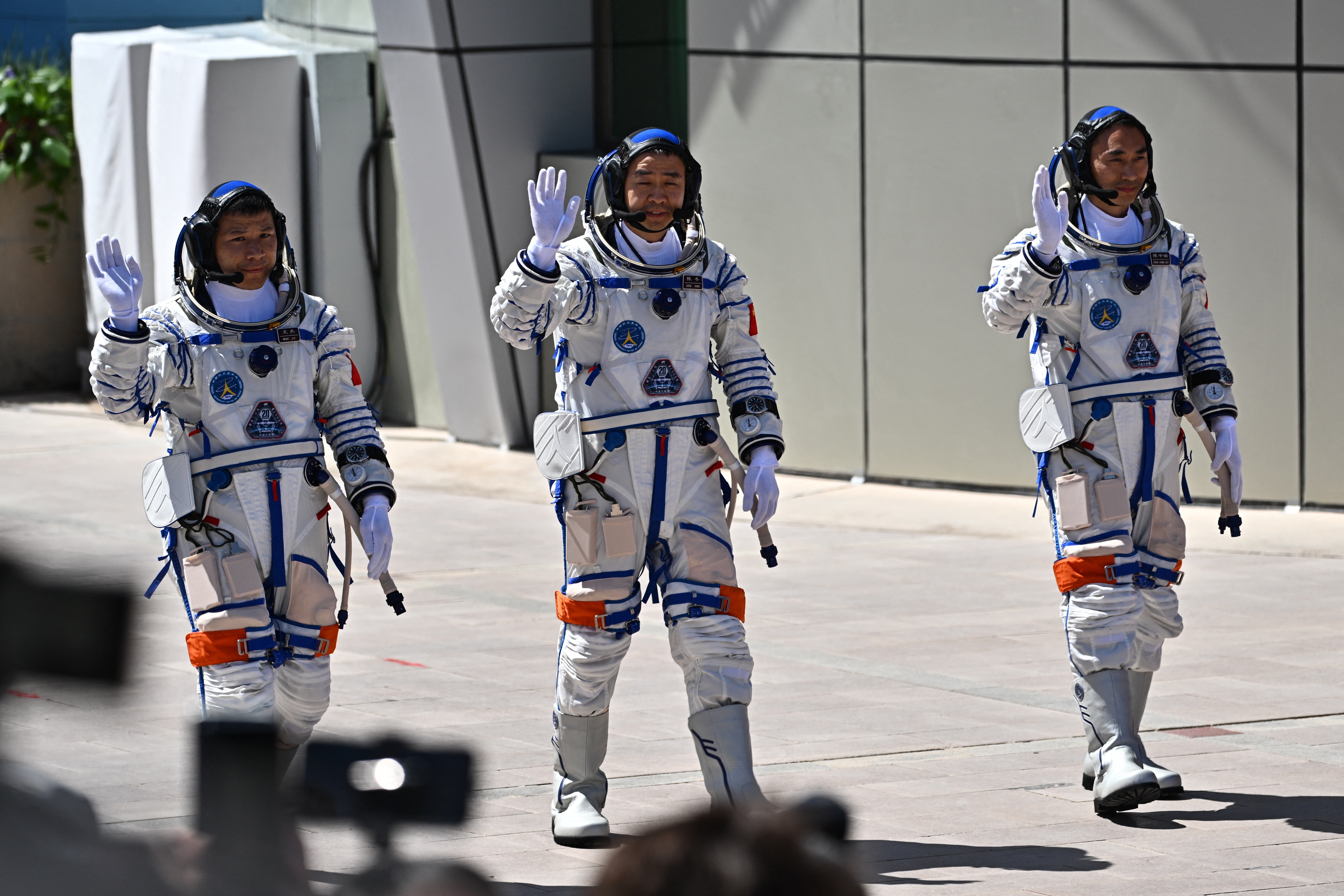 Los astronautas de la misión espacial china Shenzhou-20, Wang Jie, Chen Dong y Chen Zhongrui (de izquierda a derecha), saludan durante la ceremonia de despedida