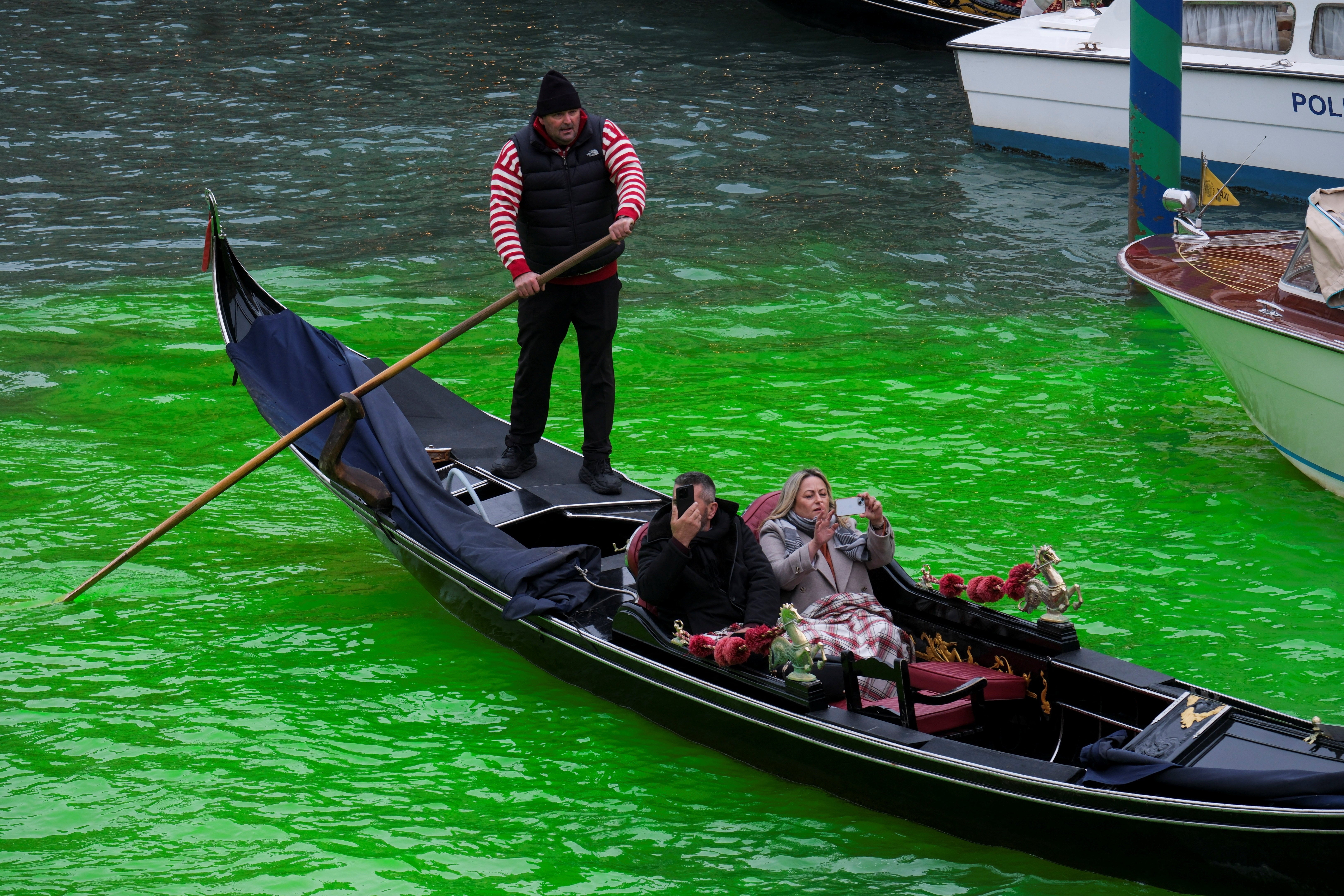 La gente disfruta de un paseo en góndola por el Gran Canal de Venecia, donde el agua de la vía acuática se tiñó de verde