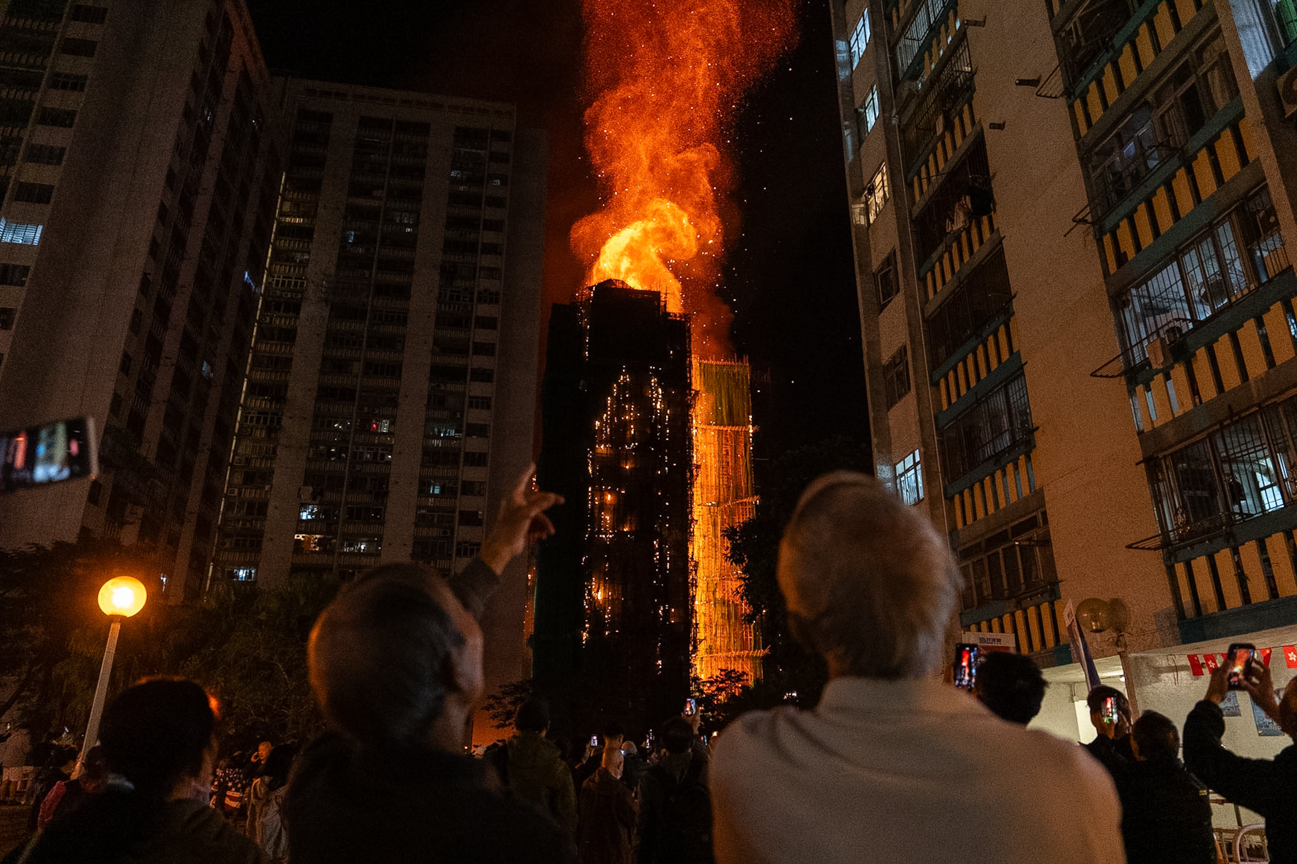 Varias personas observan las llamas que envuelven un edificio en Hong Kong