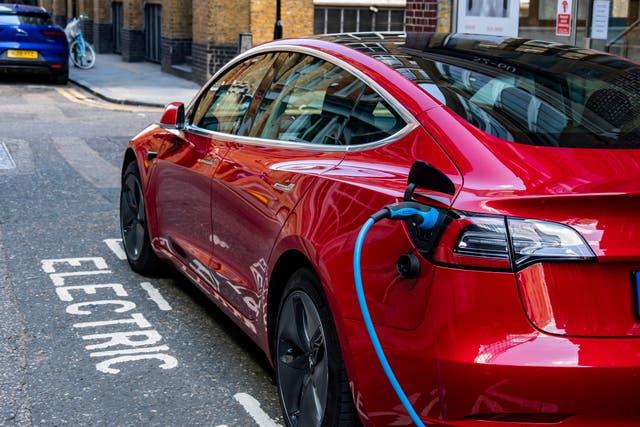 <p>Un Tesla Model 3 rojo se carga en la calle. Conductores de Tesla advierten que las puertas eléctricas y las manijas al ras del Model 3 pueden complicar la salida del vehículo ante un corte de energía o una emergencia</p>