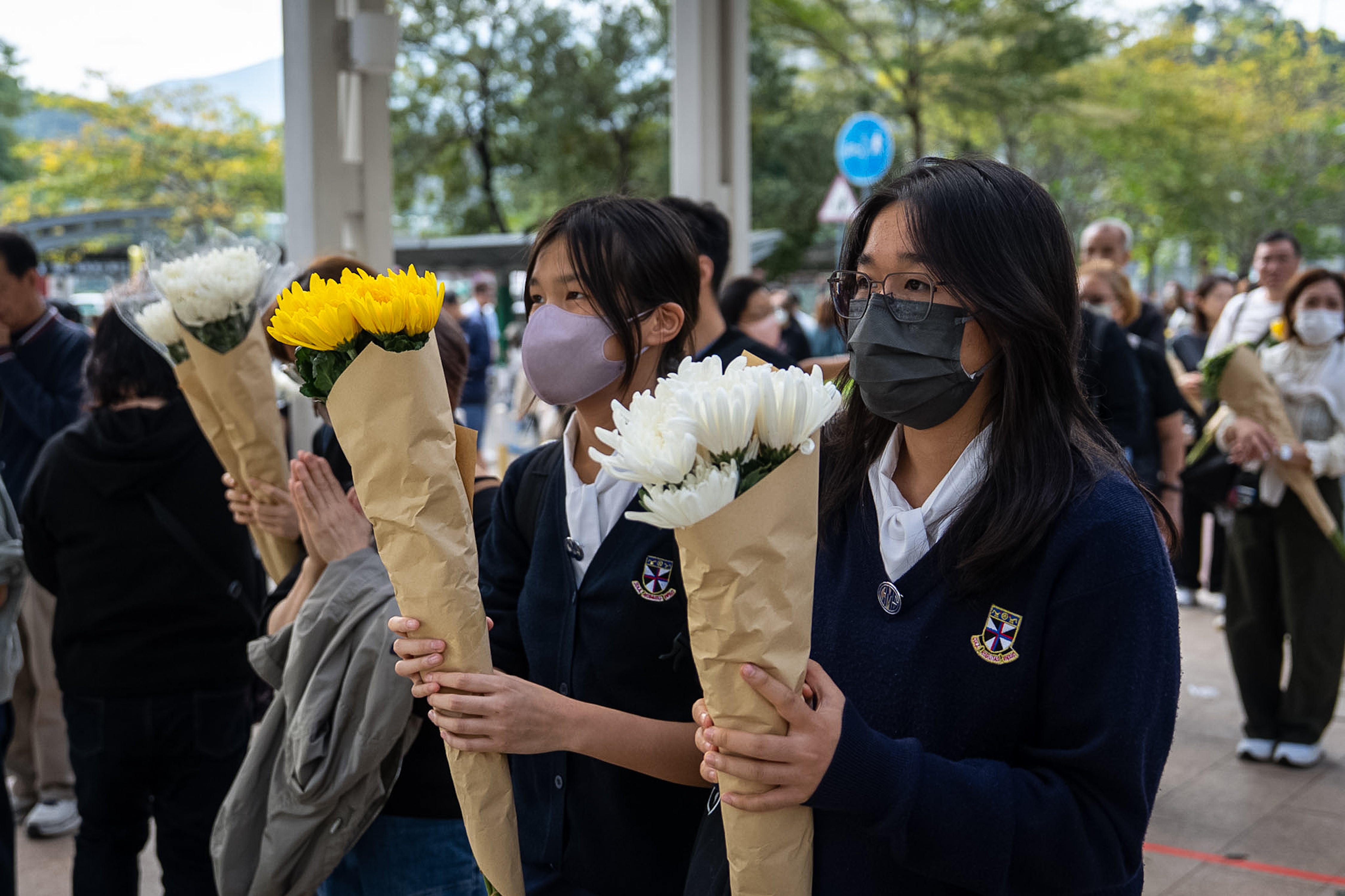 Personas ofrecen flores a las víctimas del incendio en Wang Fuk Court, en Hong Kong, el 1 de diciembre de 2025