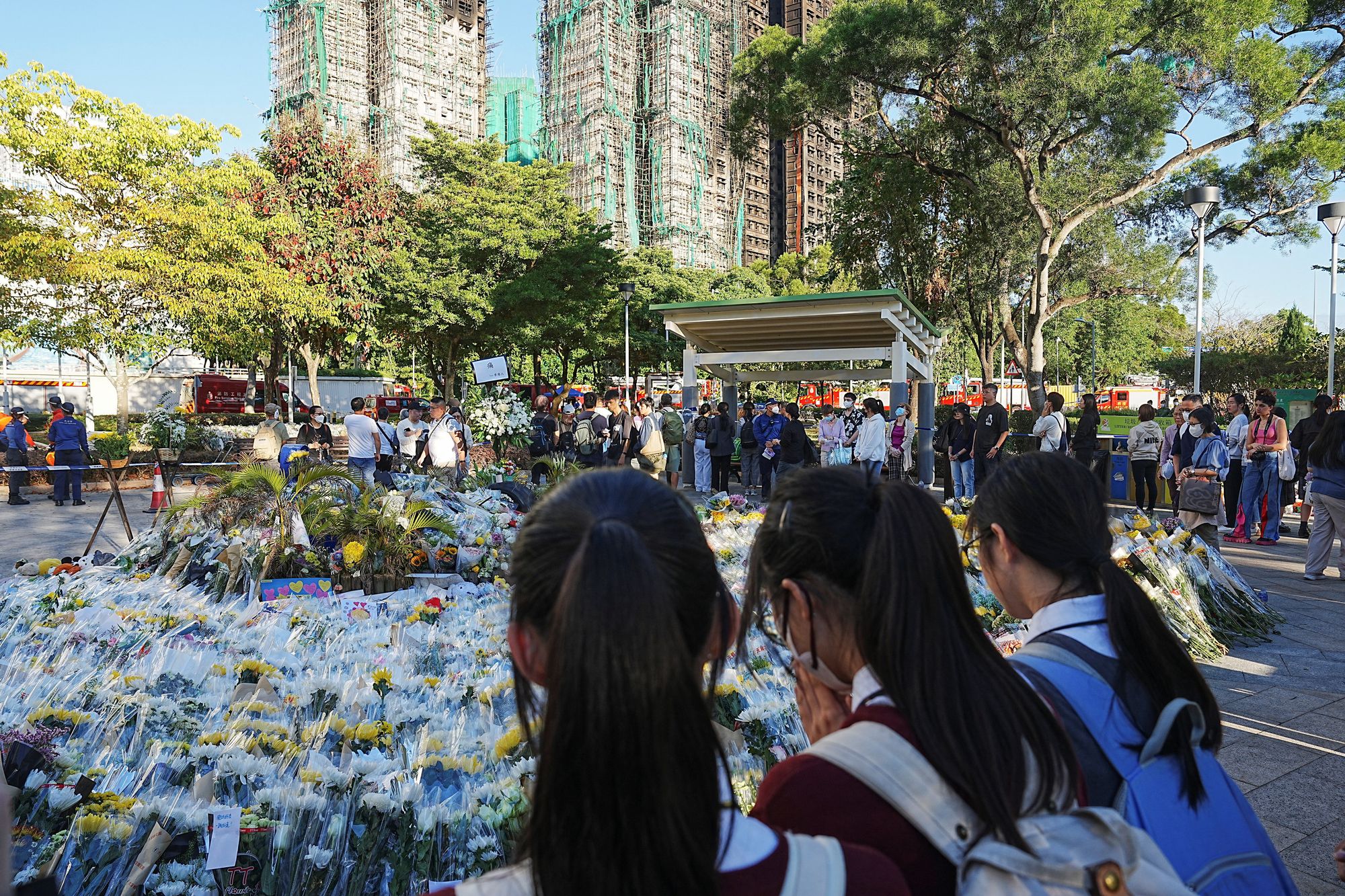 Personas dejan flores en un memorial improvisado cerca del complejo Wang Fuk Court, en Tai Po, Hong Kong