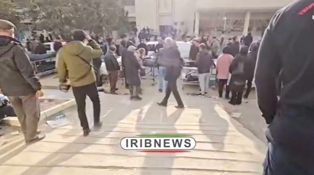 <p>Dolientes caminan entre los cuerpos dispuestos dentro de varios almacenes e incluso a lo largo de una vía interna en Teherán</p>