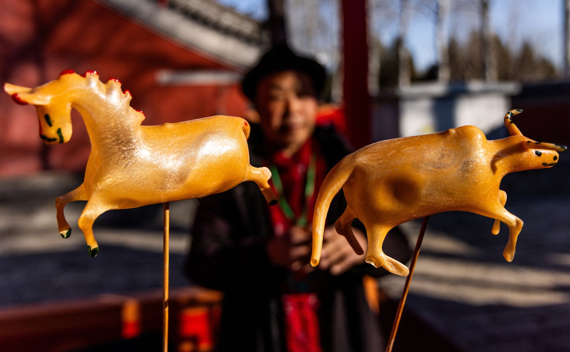 Un vendedor observa las figuras de un caballo y un buey en un mercadillo festivo el primer día del Año Nuevo lunar del caballo en el Templo Niangniang de Pekín, China.
