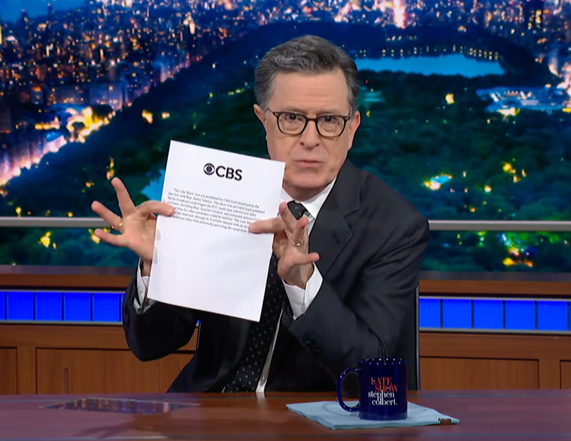 Stephen Colbert sostiene una copia impresa de la declaración de CBS sobre la edición del martes de The Late Show.