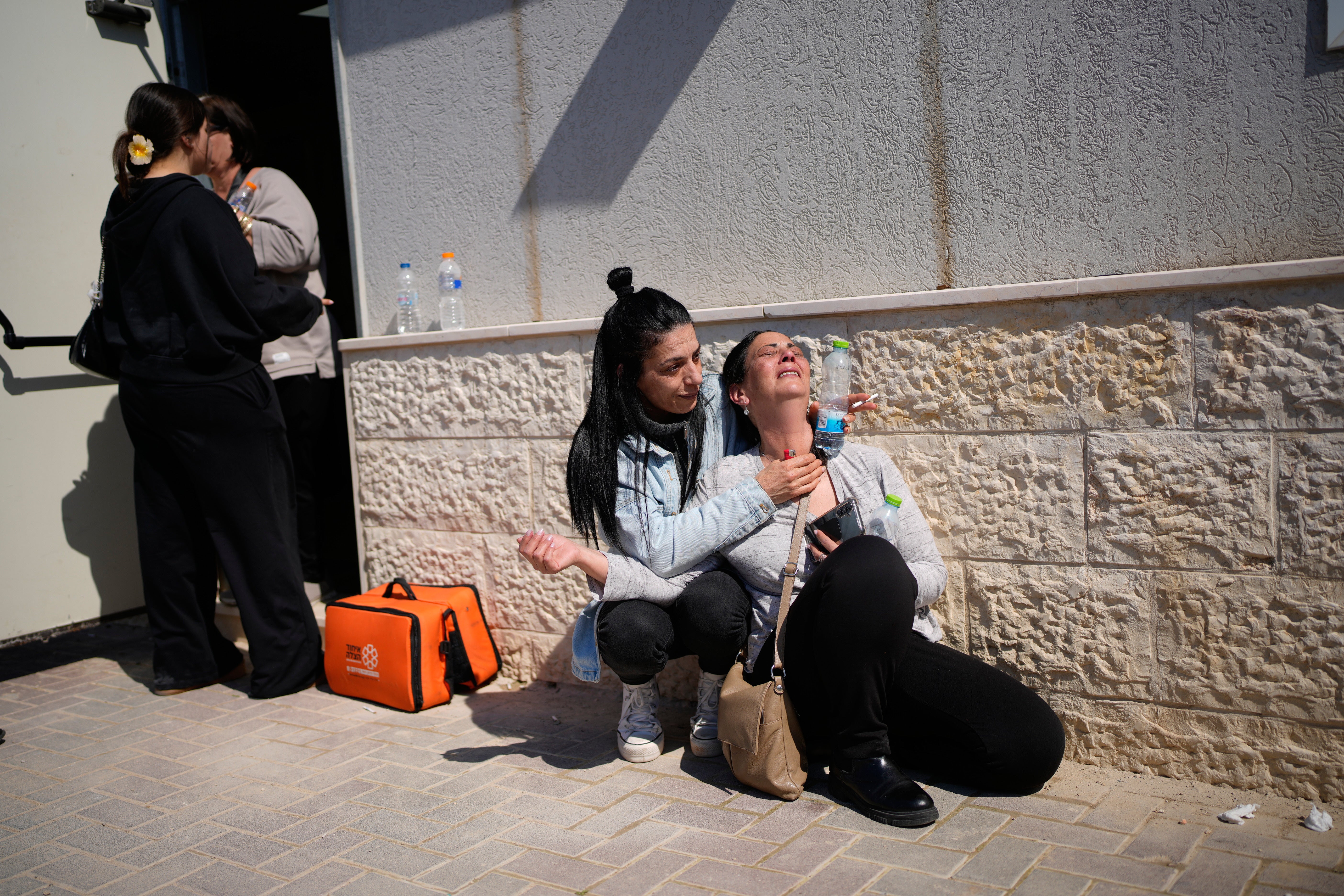 Familiares y dolientes se cubren mientras las sirenas antiaéreas suenan por misiles lanzados por Irán hacia Israel durante el funeral de Sarah Elimelech y su hija Ronit, quienes fueron asesinadas en un ataque con misiles iraníes en Beit Shemesh