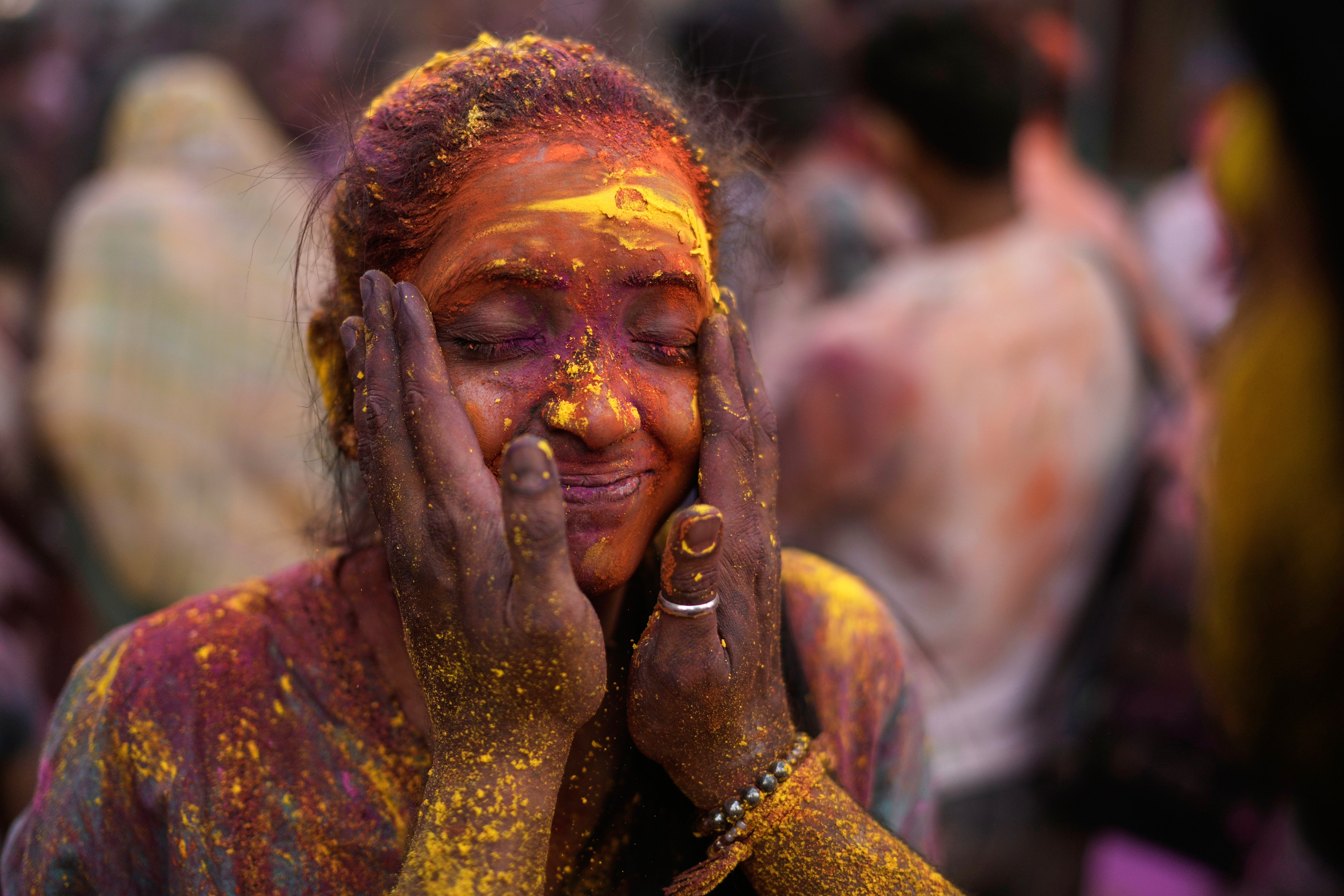 Una mujer se embadurna la cara con polvos de colores mientras celebra Holi en Hyderabad