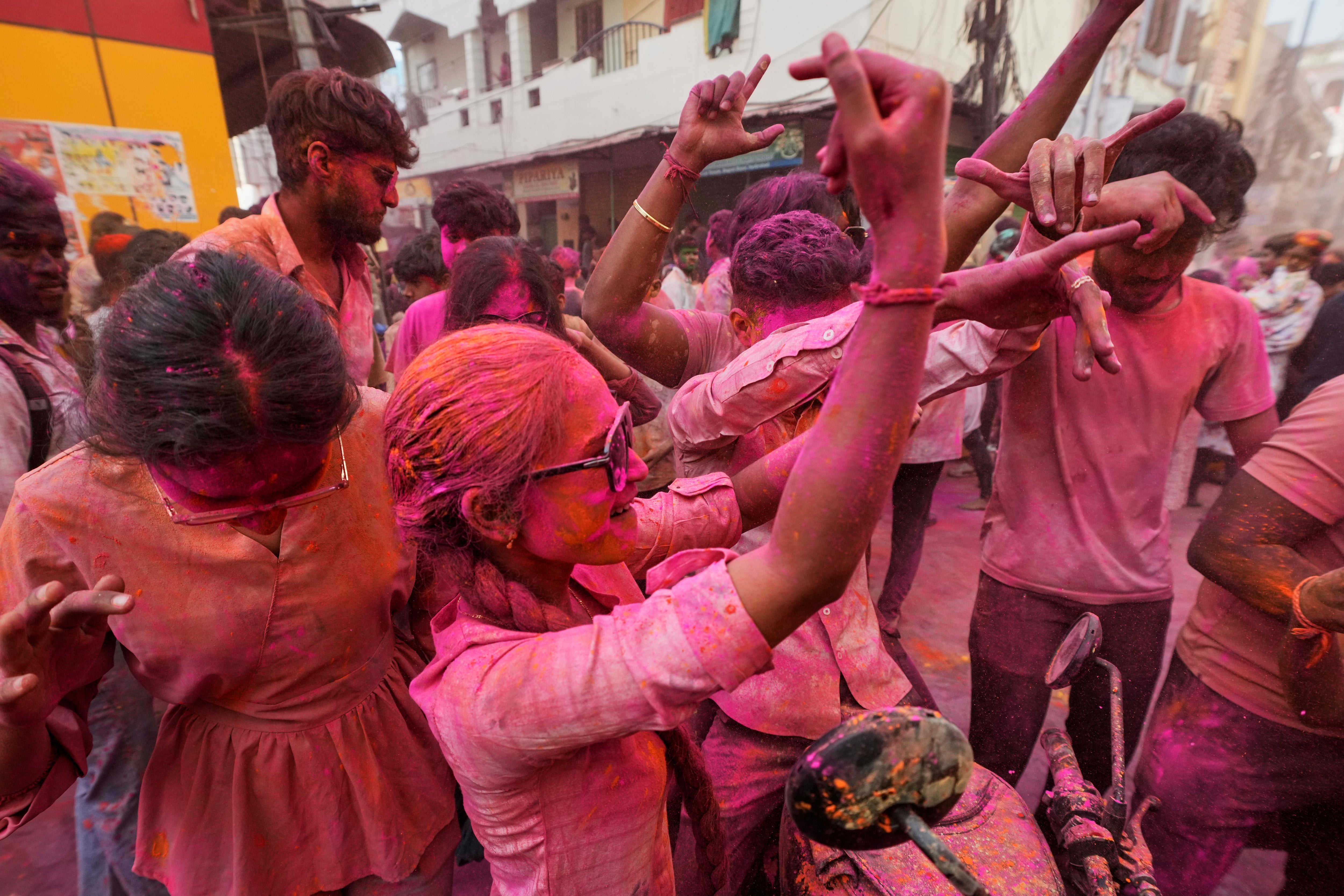 Personas manchadas con polvos de colores bailan durante una celebración de Holi en Hyderabad