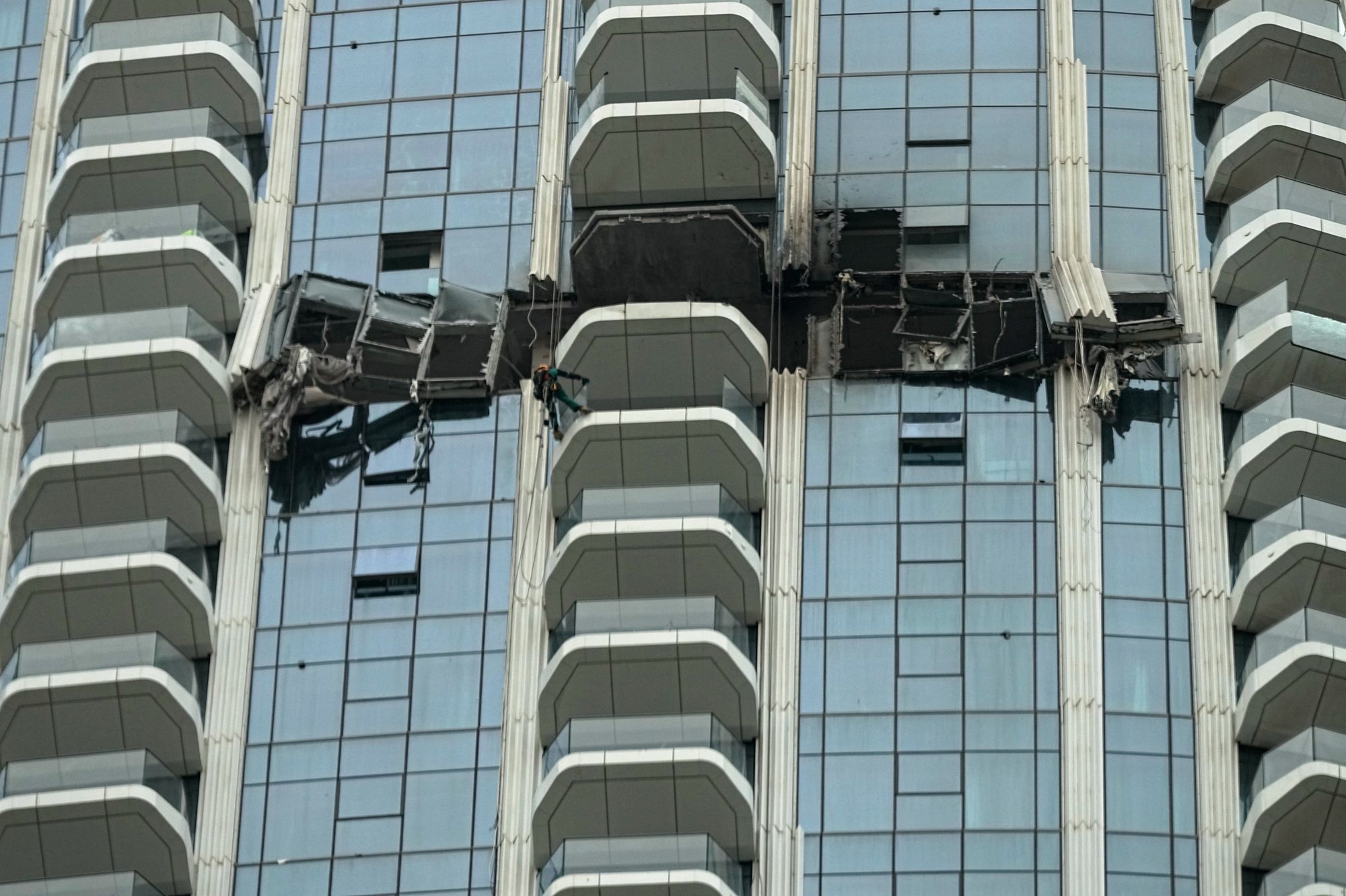 Trabajadores inspeccionan los daños en el hotel Address Creek Harbour después de que un dron impactara el edificio en Dubái el jueves