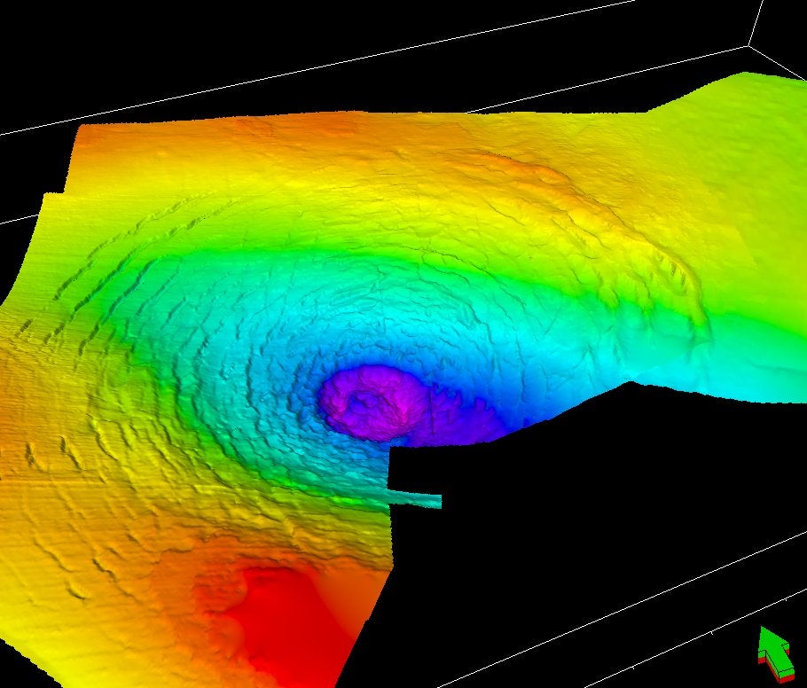 Vista en perspectiva de la superficie caliza, mirando hacia el noreste, mostrando el cráter central y los anillos que lo rodean. Los falsos colores indican la profundidad (rojo/amarillo = poco profundo; azul/morado = profundo)