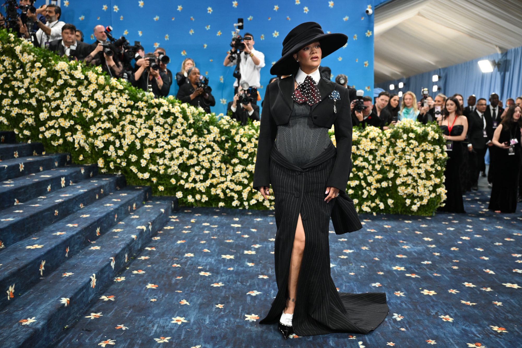Rihanna en la alfombra roja de la Met Gala de 2025. El fondo azul medianoche y los narcisos amarillos fueron pintados a mano sobre la alfombra roja de la Gala del Met de 2025, tras haber sido confeccionada a lo largo de 90 días en la India