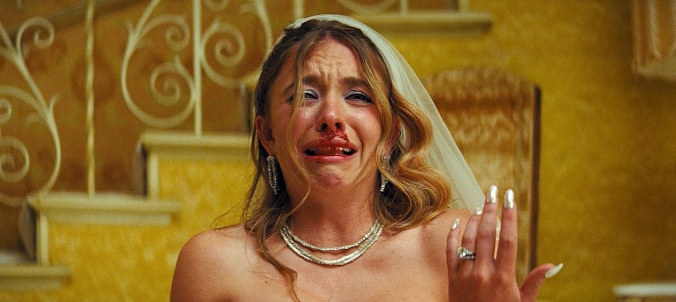 Cassie, personaje de Sydney Sweeney, llora con su vestido de novia mientras Nate, interpretado por Jacob Elordi, es golpeado por cobradores en su noche de bodas