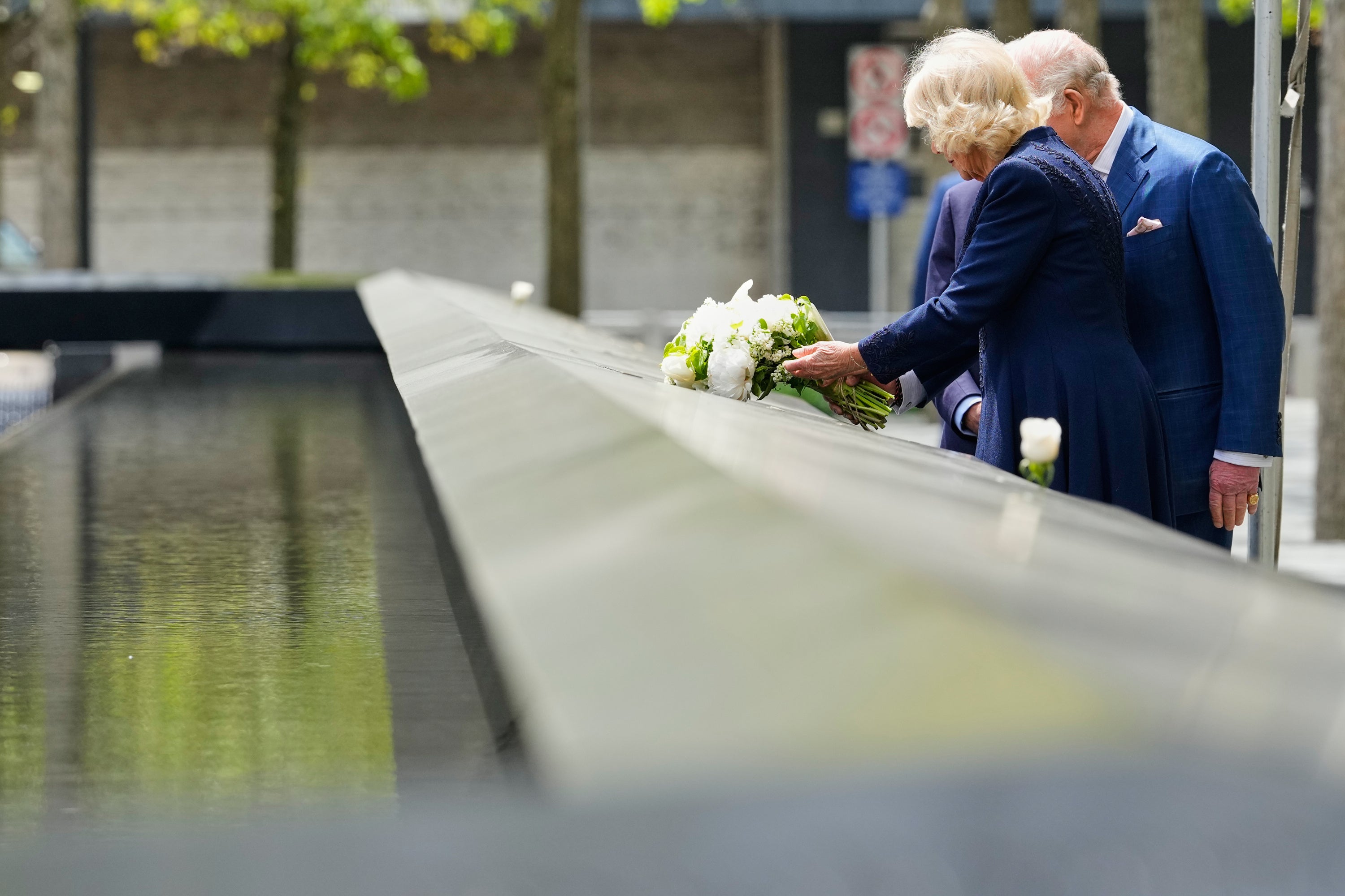 La reina Camilla deposita flores en el monumento conmemorativo del 11-S durante una visita junto al rey Carlos III de Inglaterra y el exalcalde de Nueva York Michael Bloomberg