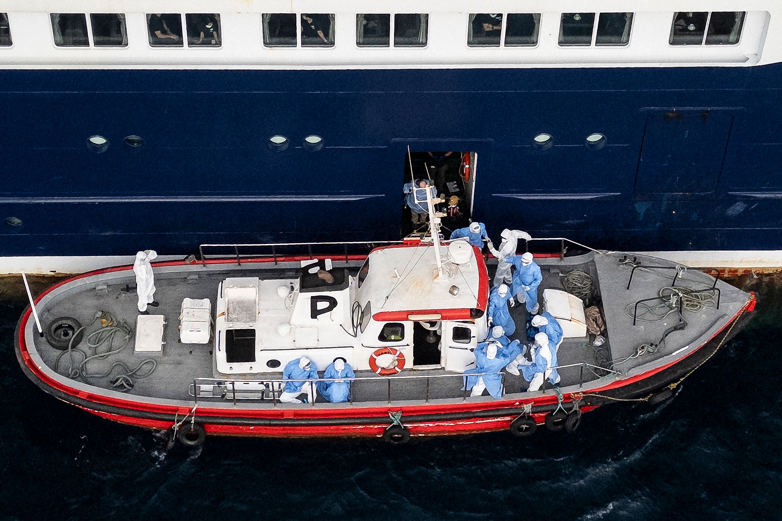 El personal sanitario ayuda a los pacientes a subir a una embarcación desde el crucero MV ‘Hondius’