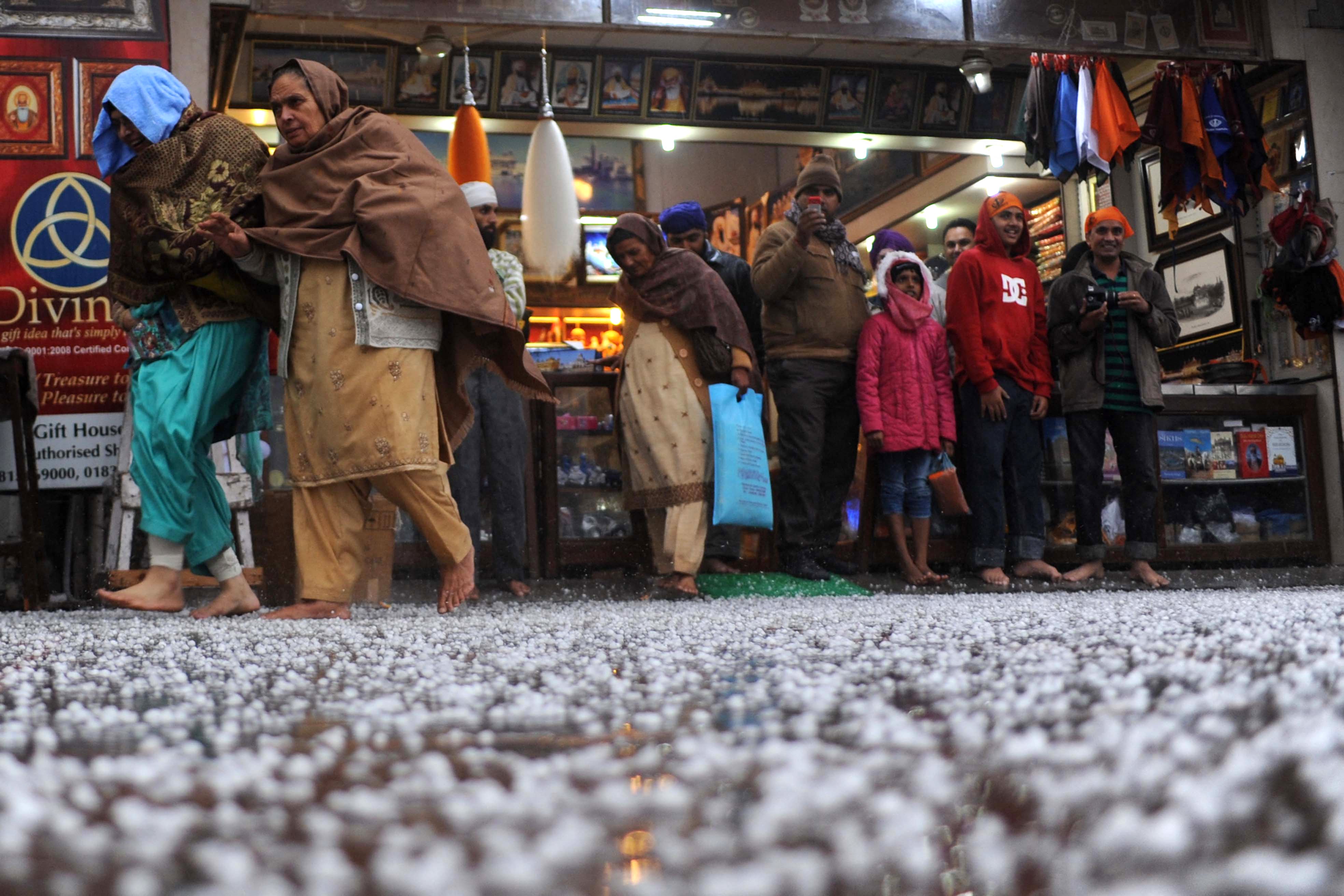 Archivo. Varias personas se refugian frente a una tienda de regalos tras una granizada en Amritsar, India